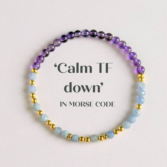 Amethyst and tanzanite elasticated stretch crystal morse code bracelet that spells out the words ‘Calm TF down’ in a combination of 4mm round amethyst beads, 4mm faceted tanzanite beads and either sterling silver or gold vermeil 3mm round beads. The words start and end at the rondelle spacer beads.