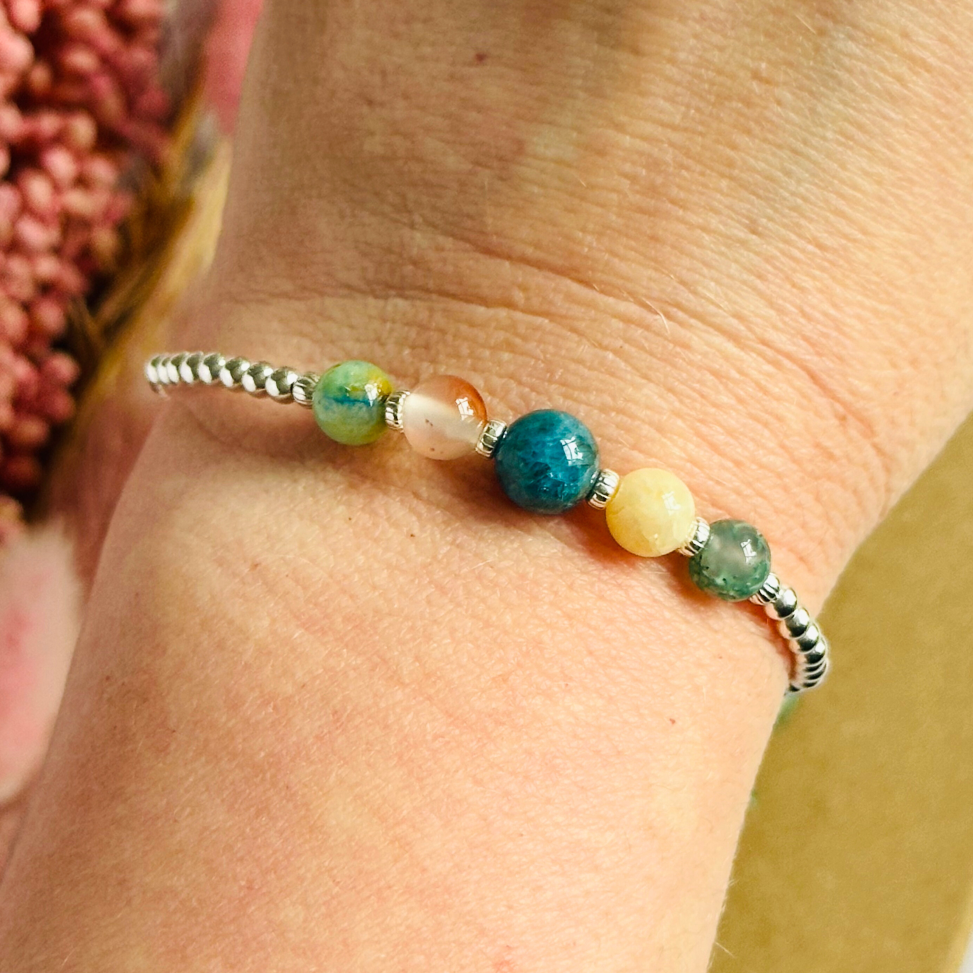 This sterling silver Gemini bracelet is made with a selection of five healing crystals all believed to resonate with the Gemini zodiac sign. The central bead is 8mm, the other four are 6mm. On an elasticated band of 3mm sterling silver beads with corrugated accent beads. Featuring chrysocolla, dendritic agate, apatite, yellow calcite and moss agate.