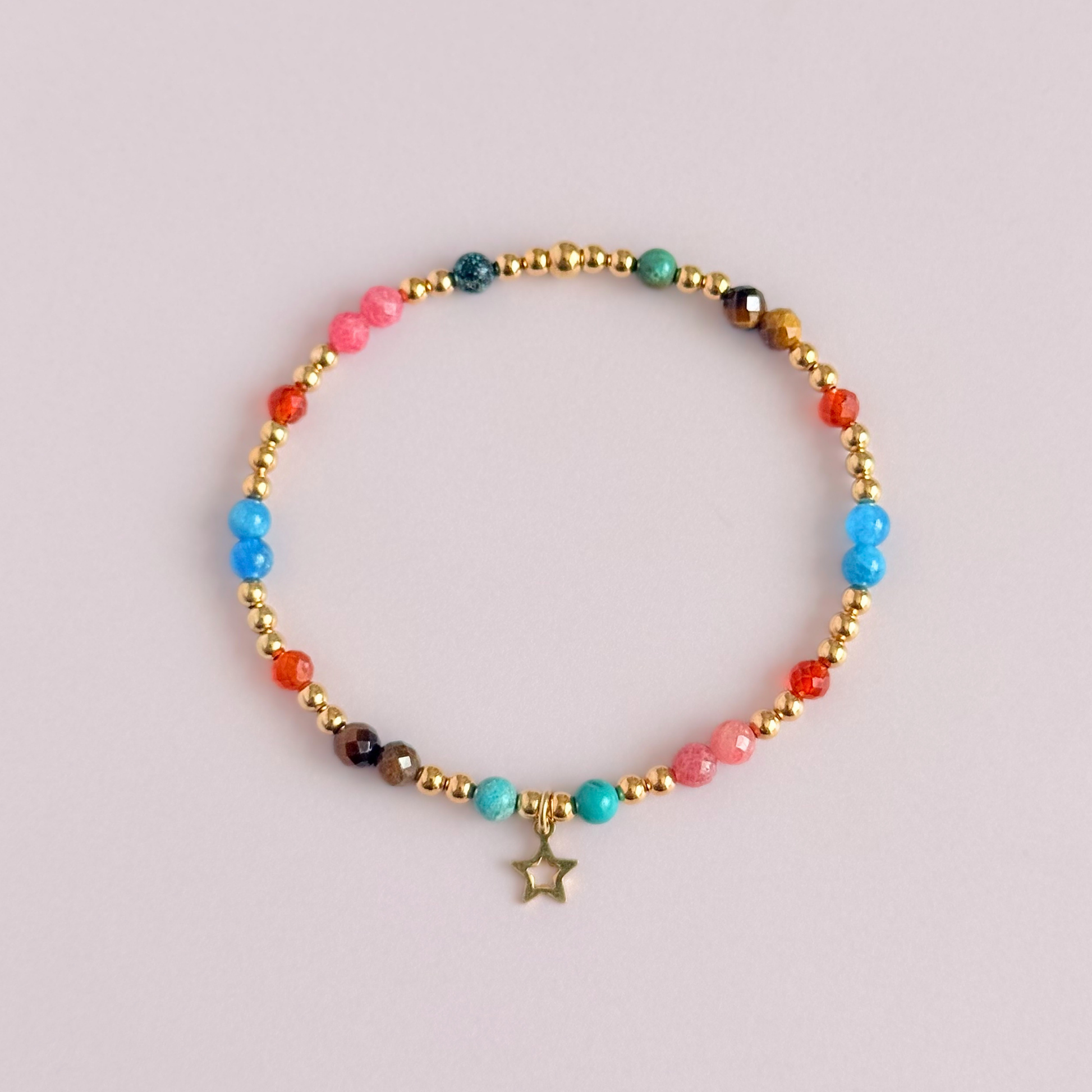 'Hot girl summer' gold vermeil dainty beaded bracelet with tigers eye, turquoise, apatite, carnelian and rhodochrosite. With a beautiful open star charm.Made with round 3mm gold vermeil beads and 4mm smooth and faceted round crystal gemstone beads. Pictured from above, against a pink background.
