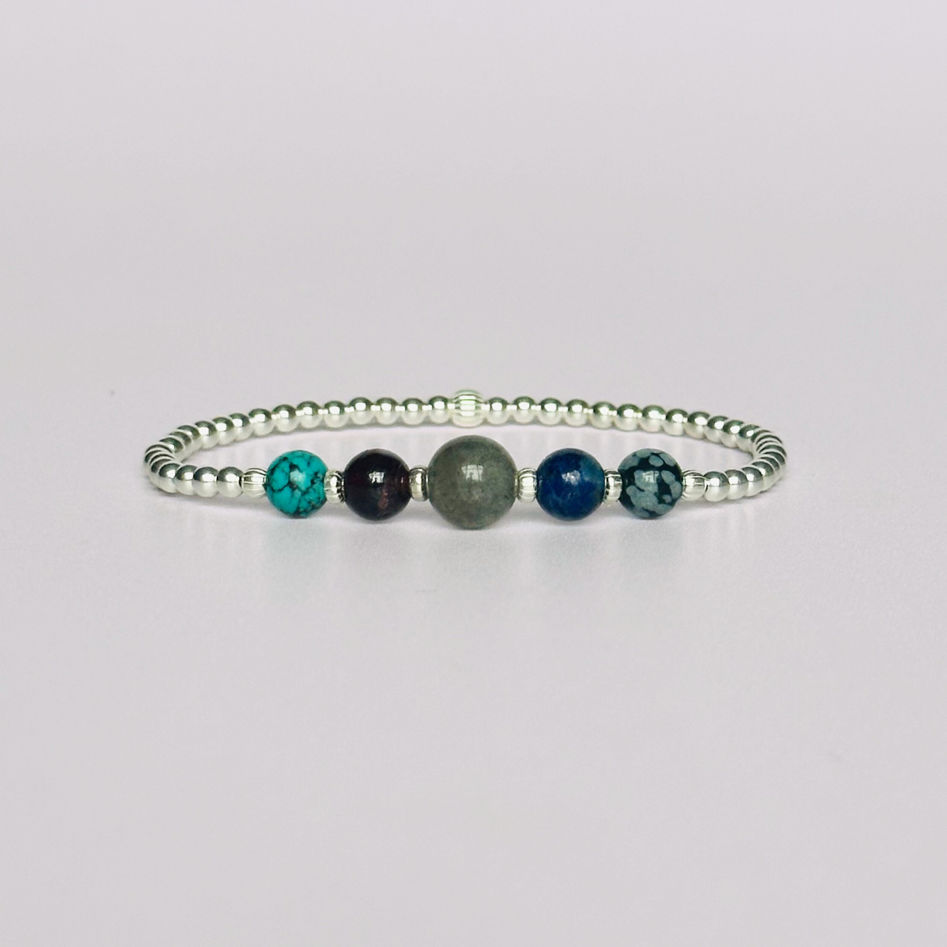 This sterling silver Sagittarius bracelet is made with a selection of five healing crystals all believed to resonate with the Sagittarius zodiac sign. The central bead is 8mm, the other four are 6mm. On an elasticated band of 3mm sterling silver beads with corrugated accent beads. Featuring garnet, labradorite, lapis lazuli, snowflake obsidian and turquoise.