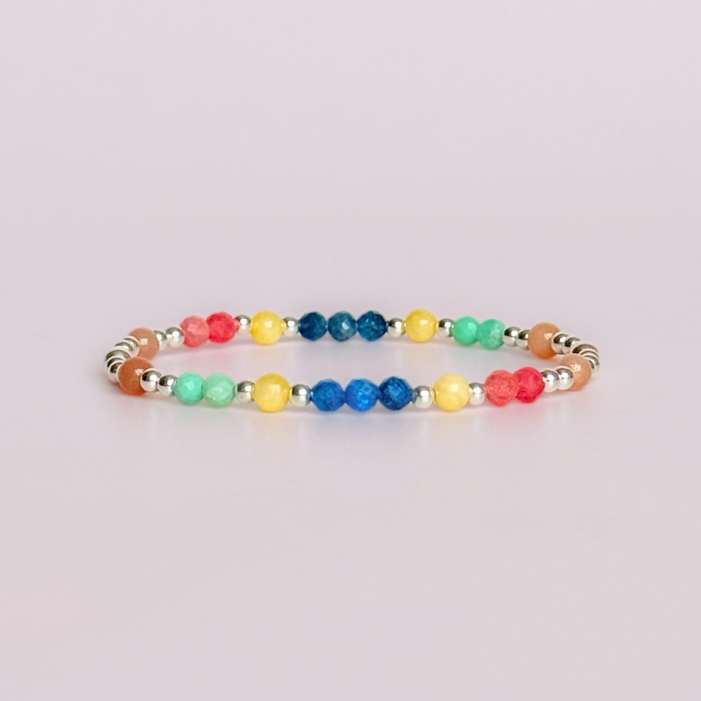 'Key West' sterling silver dainty beaded bracelet with apatite, rhodochrosite, yellow calcite, chrysoprase and peach moonstone. Made with round 3mm sterling silver beads and 4mm smooth and faceted round crystal gemstone beads. Pictured against a pink background
