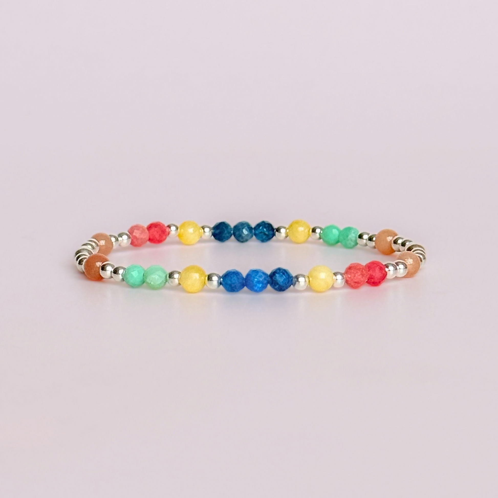 'Key West' sterling silver dainty beaded bracelet with apatite, rhodochrosite, yellow calcite, chrysoprase and peach moonstone. Made with round 3mm sterling silver beads and 4mm smooth and faceted round crystal gemstone beads. Pictured against a pink background