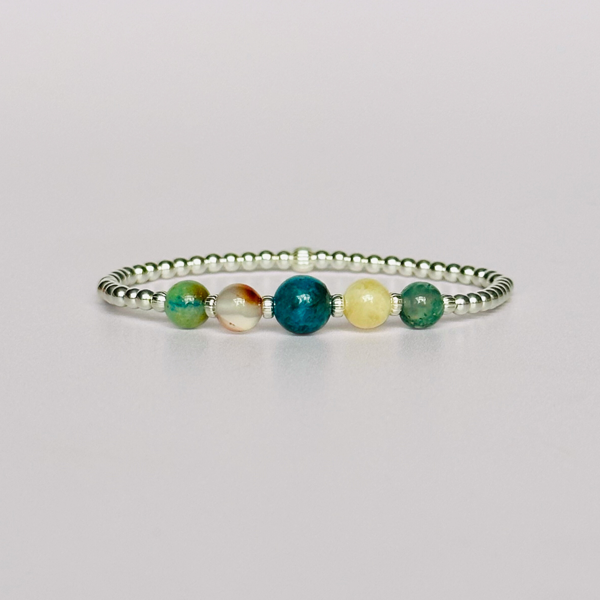 This sterling silver Gemini bracelet is made with a selection of five healing crystals all believed to resonate with the Gemini zodiac sign. The central bead is 8mm, the other four are 6mm. On an elasticated band of 3mm sterling silver beads with corrugated accent beads. Featuring chrysocolla, dendritic agate, apatite, yellow calcite and moss agate.