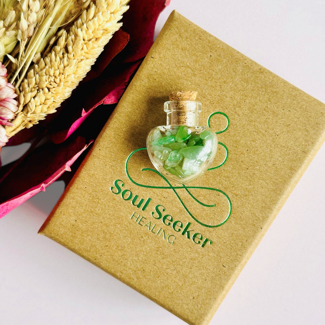 A pretty heart shaped mini glass bottle filled with powerful, ethically mined green aventurine crystal chips, known for their properties regarding good luck, abundance and success. Presented on a card with the words ‘may good luck be your constant companion.’ This bottle measures approximately 28mm x 23mm, including cork when it is pushed in.