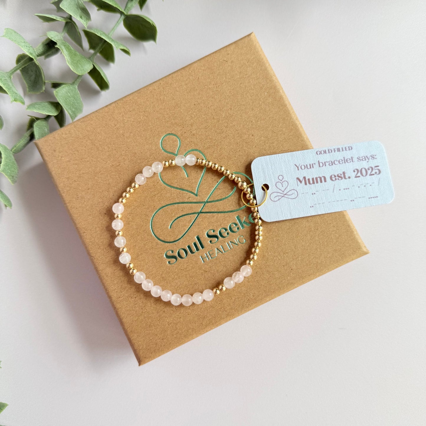 Morse code secret message bracelet spelling out the words Mum est. 2025 in gold filled and rose quartz crystal beads. elasticated with 4mm rose quartz beads and 3mm gold filled beads.