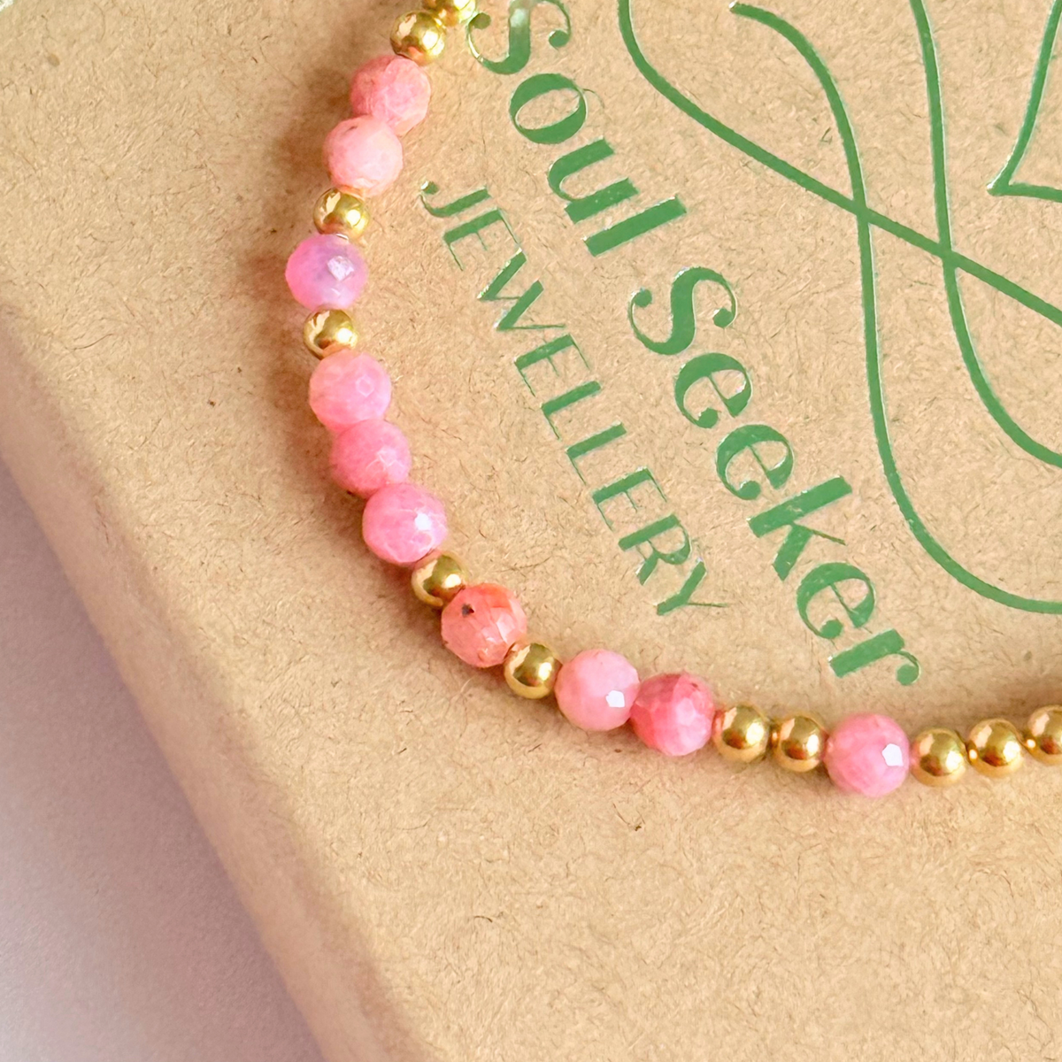 Dainty, minimalist gold vermeil and pink tourmaline October birthstone stacking bracelet. Made with 4mm faceted pink tourmaline beads and 3mm gold vermeil round beads. Elasticated for comfort. Pictured close up, on top of the gift box