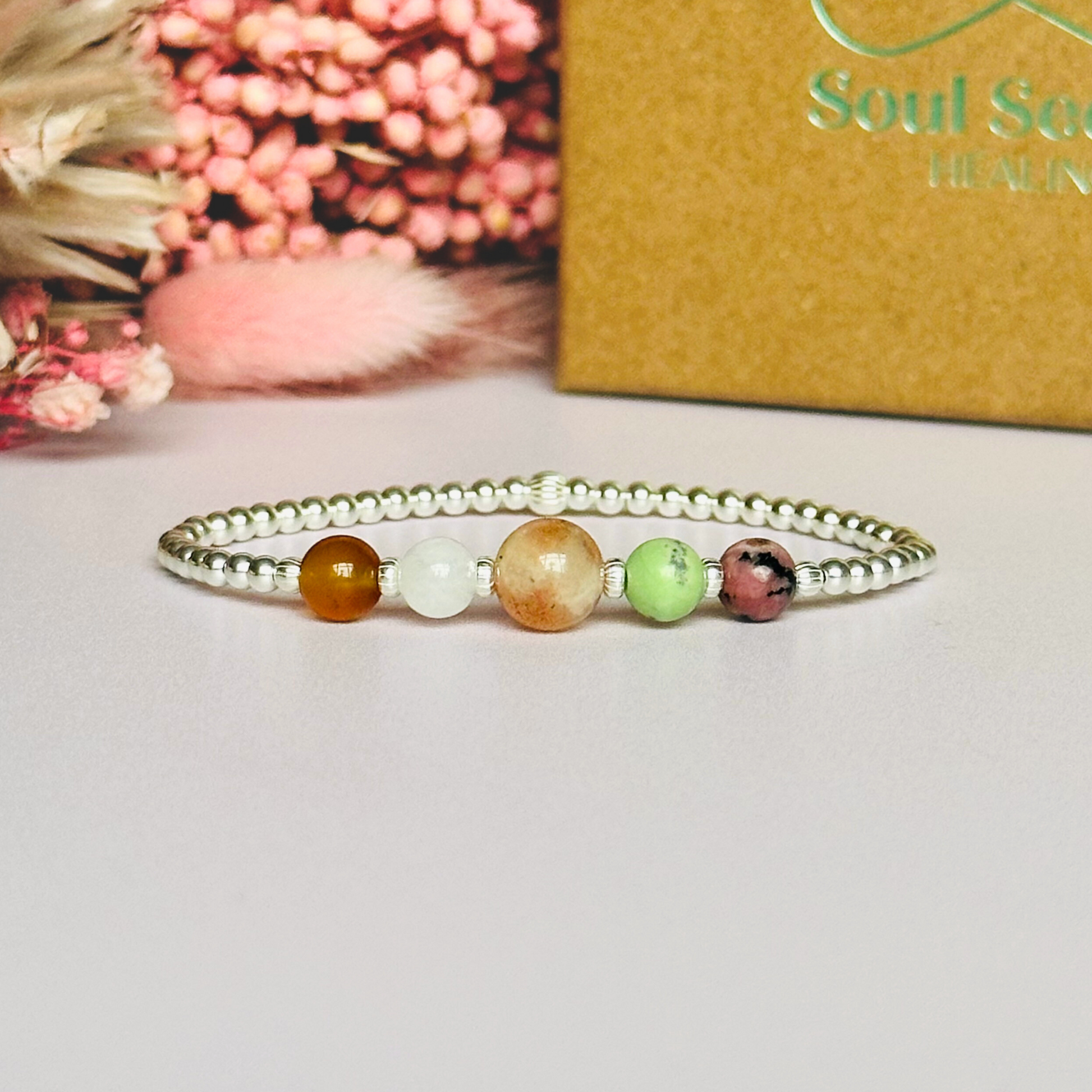 This sterling silver Cancer bracelet is made with a selection of five healing crystals all believed to resonate with the Cancer zodiac sign. The central bead is 8mm, the other four are 6mm. On an elasticated band of 3mm sterling silver beads with corrugated accent beads. Featuring chrysoprase, rhodonite, sunstone, carnelian and moonstone.