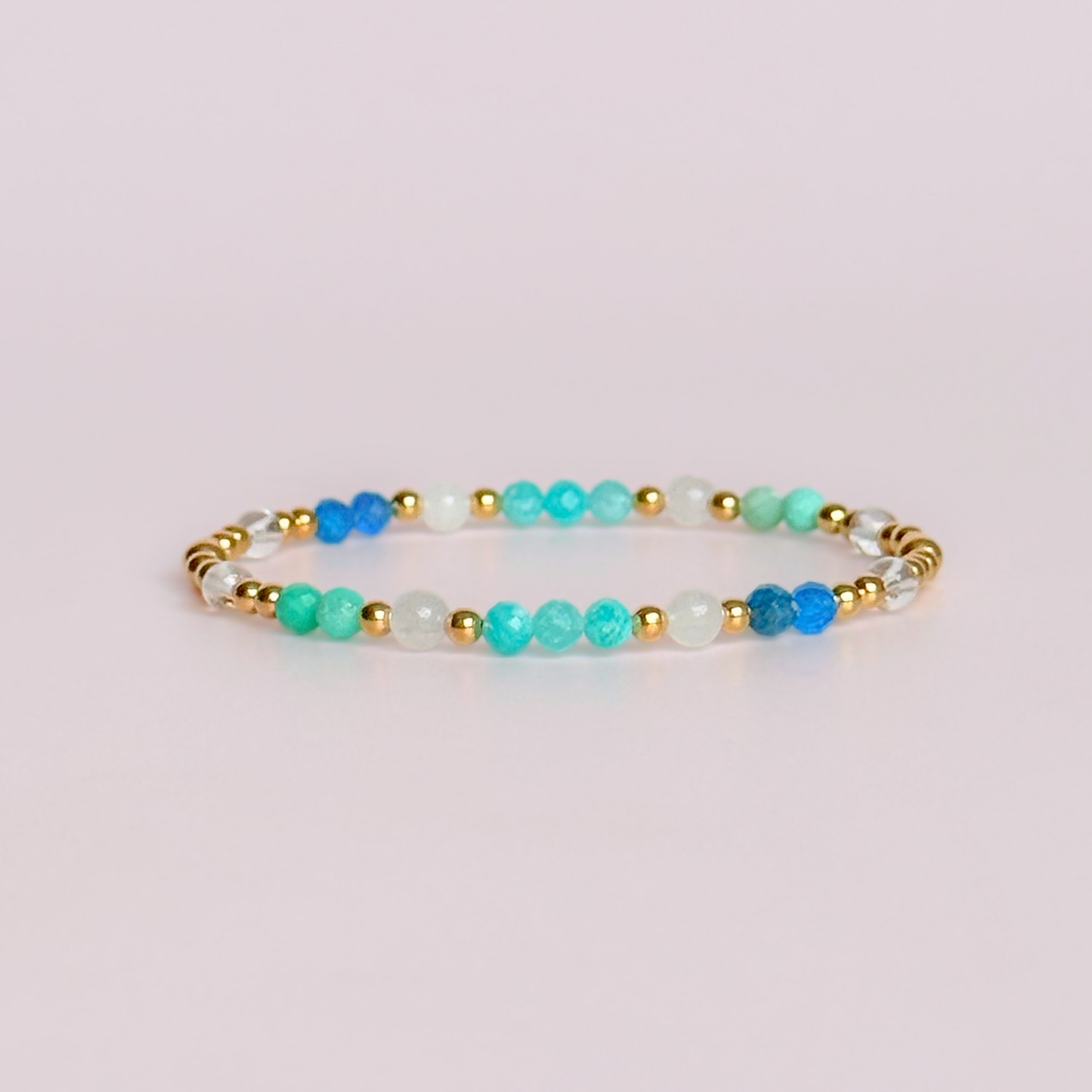 ‘Caribbean Dream' gold vermeil dainty beaded bracelet with white jade, chrysoprase, amazonite, apatite and clear quartz. Made with round 3mm gold vermeil beads and 4mm smooth and faceted round crystal gemstone beads. Pictured against a pink background 
