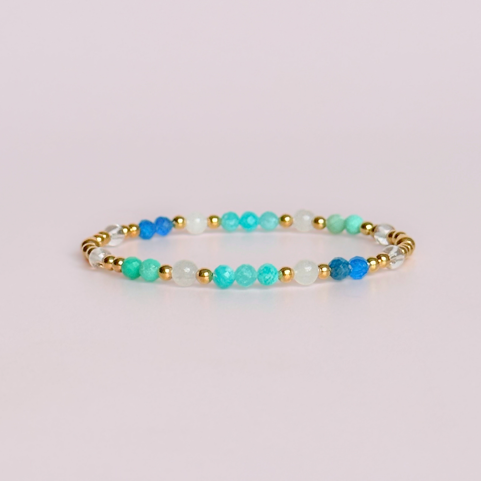 ‘Caribbean Dream' gold vermeil dainty beaded bracelet with white jade, chrysoprase, amazonite, apatite and clear quartz. Made with round 3mm gold vermeil beads and 4mm smooth and faceted round crystal gemstone beads. Pictured against a pink background 