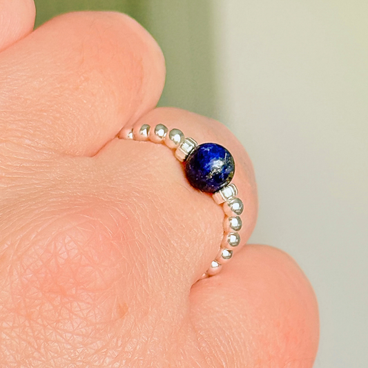 Sterling silver beaded ring featuring a 6mm lapis lazuli round bead, flanked by sterling silver corrugated beads. Elasticated for comfort.