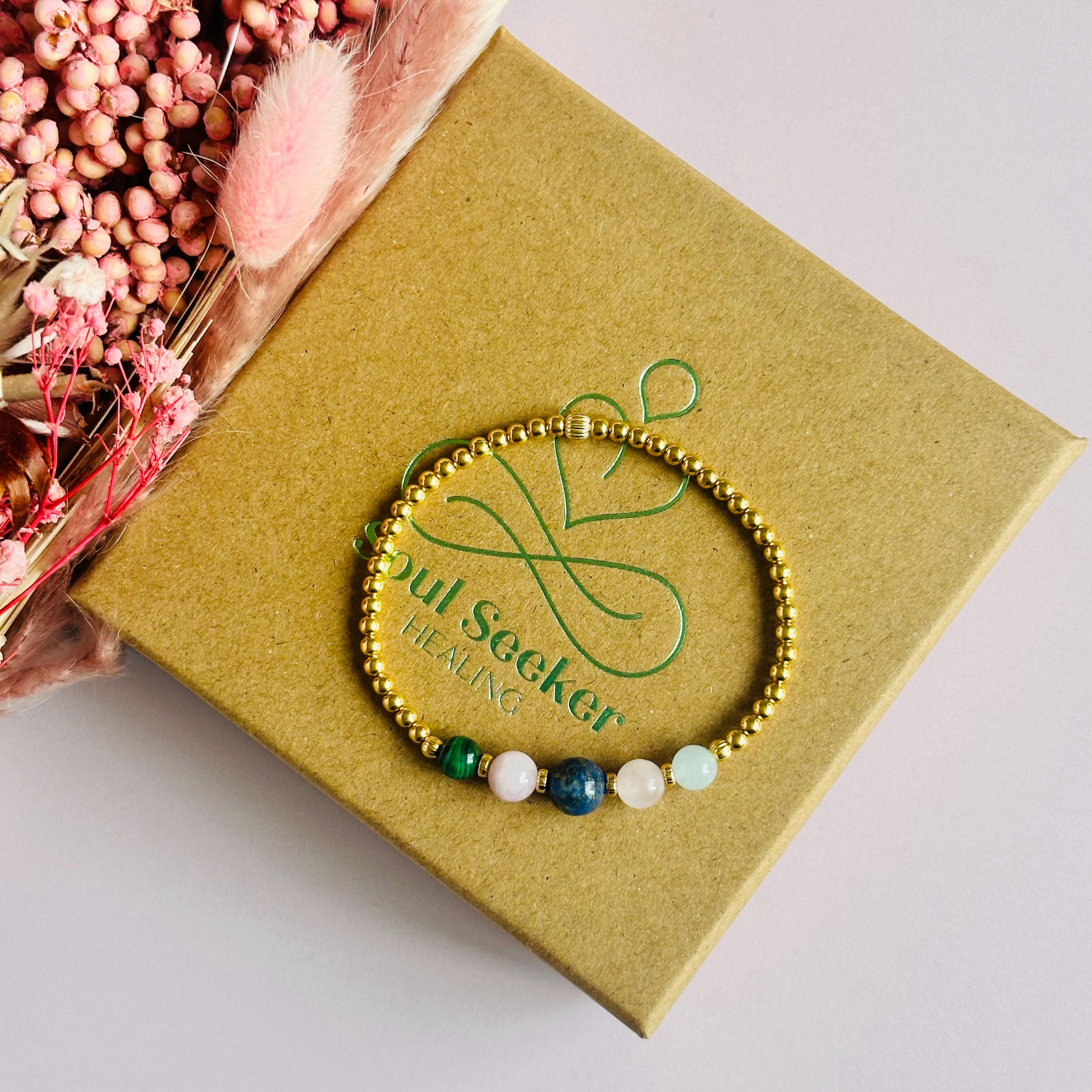 This gold vermeil Taurus bracelet is made with a selection of five healing crystals all believed to resonate with the Taurus zodiac sign. The central bead is 8mm, the other four are 6mm. On an elasticated band of 3mm gold vermeil beads with corrugated accent beads. Featuring malachite, lapis lazuli, rose quartz, kunzite and aquamarine.
