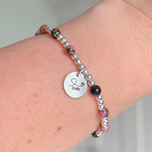 Sterling silver bracelet featuring ethically mined 4mm rhodonite crystal beads, separated by 3mm sterling silver beads. It features an 11mm sterling silver disc charm, which is engraved with a love heart and paw design, which can be personalised with your pet's name. The reverse of the charm says 'Forever in your heart x', although this side can also be personalised with your own words.