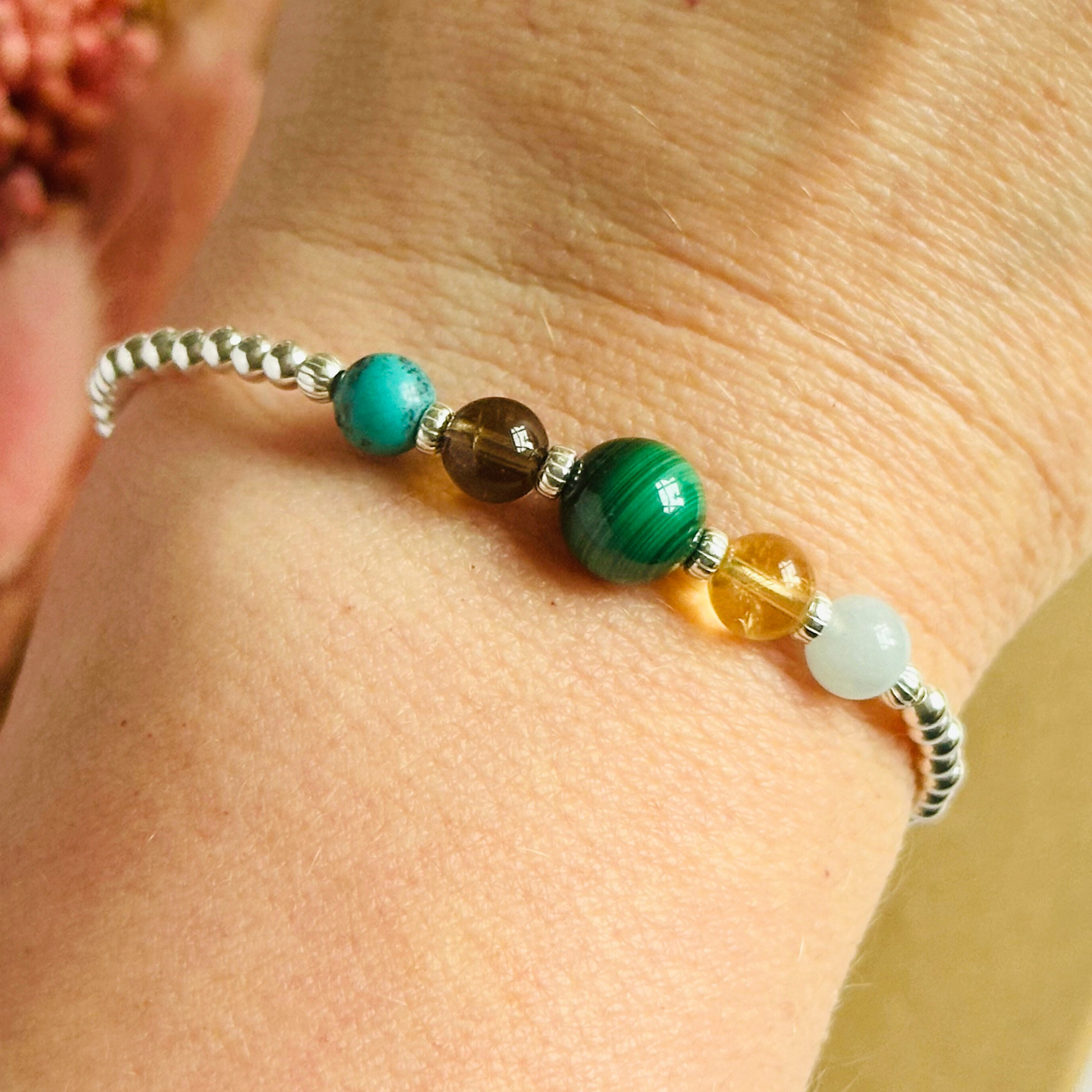 This sterling silver Scorpio bracelet is made with a selection of five healing crystals all believed to resonate with the Scorpio zodiac sign. The central bead is 8mm, the other four are 6mm. On an elasticated band of 3mm sterling silver beads with corrugated accent beads. Featuring aquamarine, citrine, malachite, smoky quartz and turquoise.