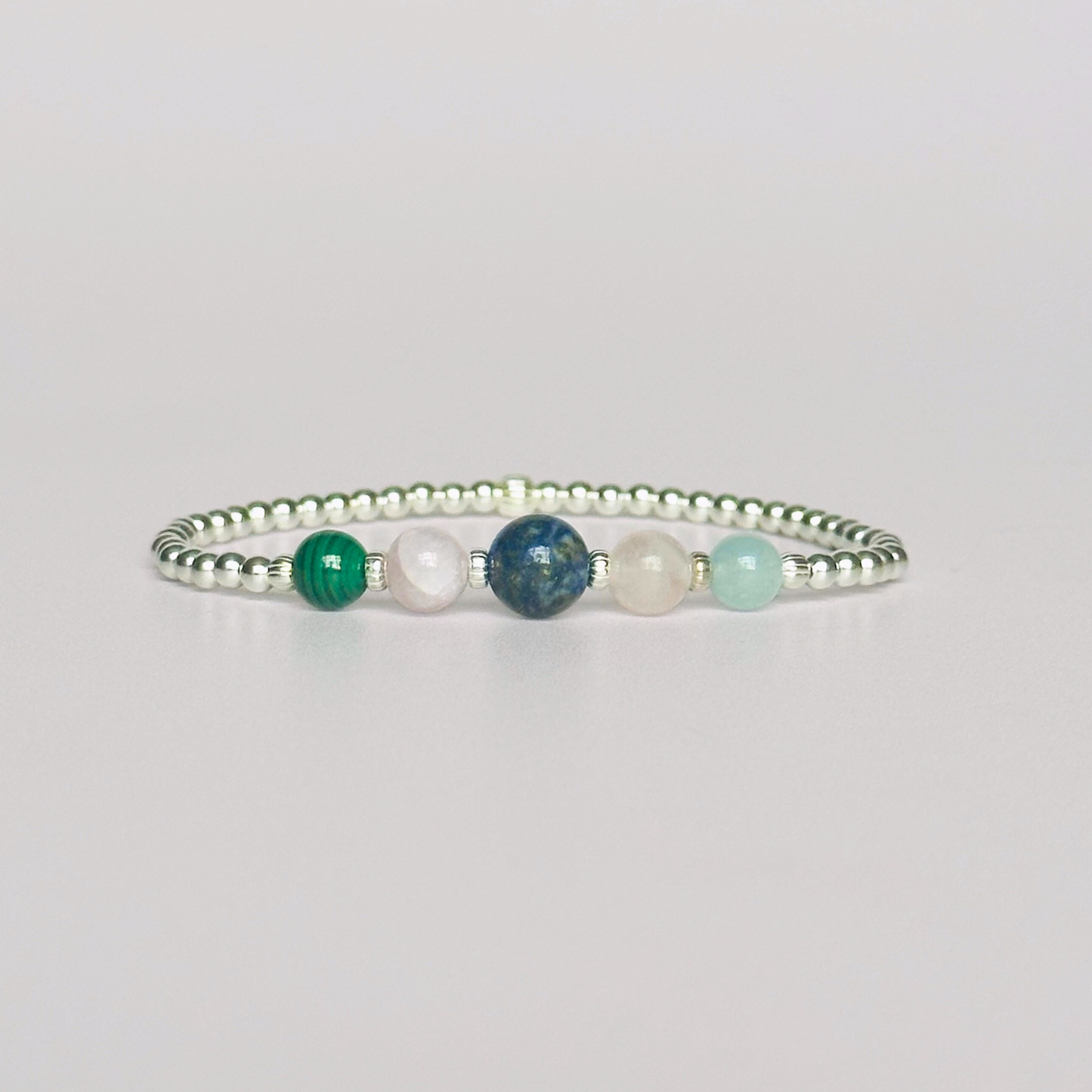 This sterling silver Taurus bracelet is made with a selection of five healing crystals all believed to resonate with the Taurus zodiac sign. The central bead is 8mm, the other four are 6mm. On an elasticated band of 3mm sterling silver beads with corrugated accent beads. Featuring malachite, lapis lazuli, rose quartz, kunzite and aquamarine.