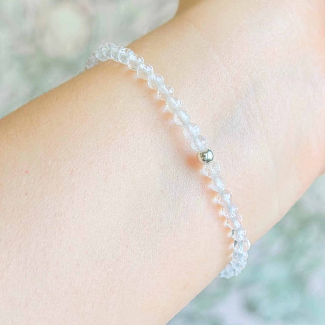 Bracelet featuring engraved wooden 777 angel number and wing beads, on the band of 4mm faceted clear quartz round crystal gemstone beads. Finished with your choice of gold vermeil, sterling silver or rose gold vermeil accent beads.