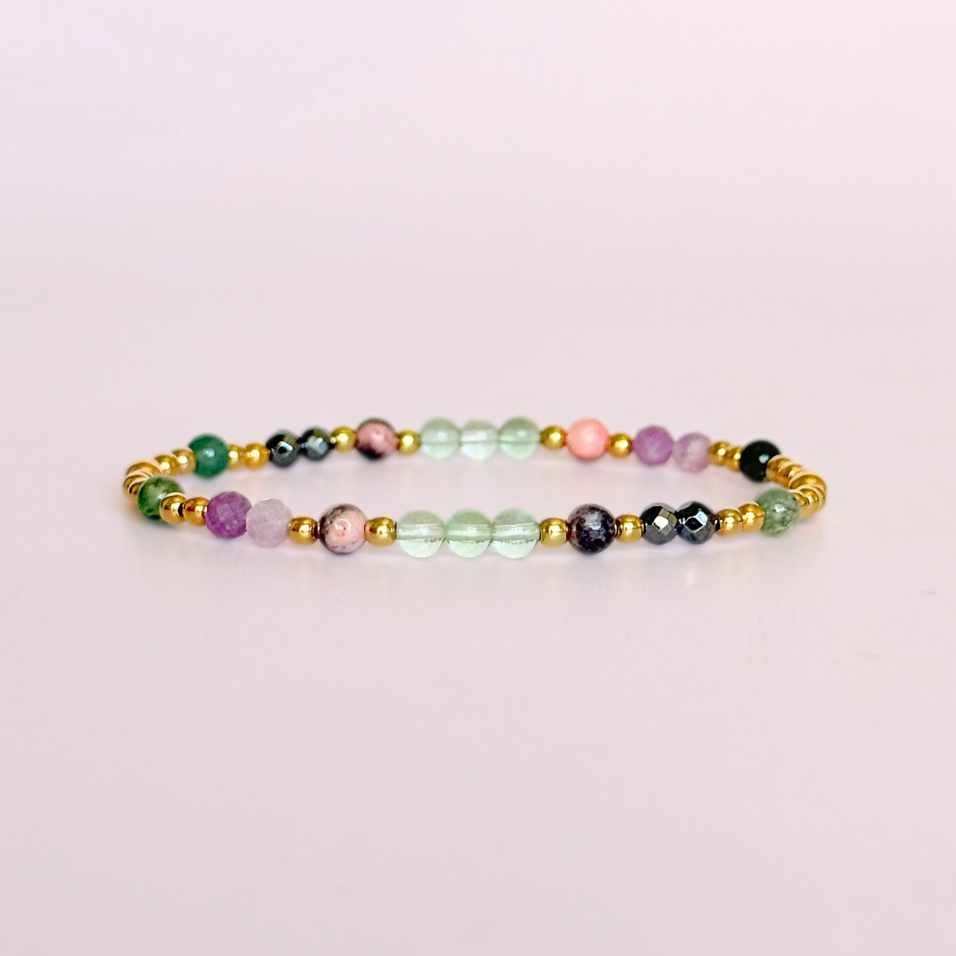 Dainty crystal bracelet featuring five crystals all believed to help with focus, clarity and overwhelm. Featuring fluorite, hematite, lepidolite, moss agate and pink zebra jasper. Featuring 3mm gold vermeil round beads and 4mm faceted round and smooth round crystal beads. Pictured against a light pink background.￼