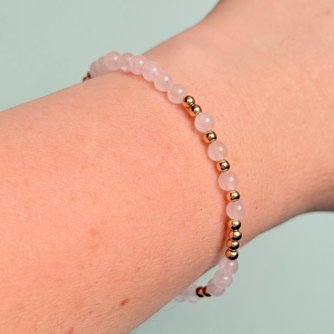 Morse code secret message bracelet spelling out the words Mum est. 2025 in gold filled and rose quartz crystal beads. elasticated with 4mm rose quartz beads and 3mm gold filled beads.