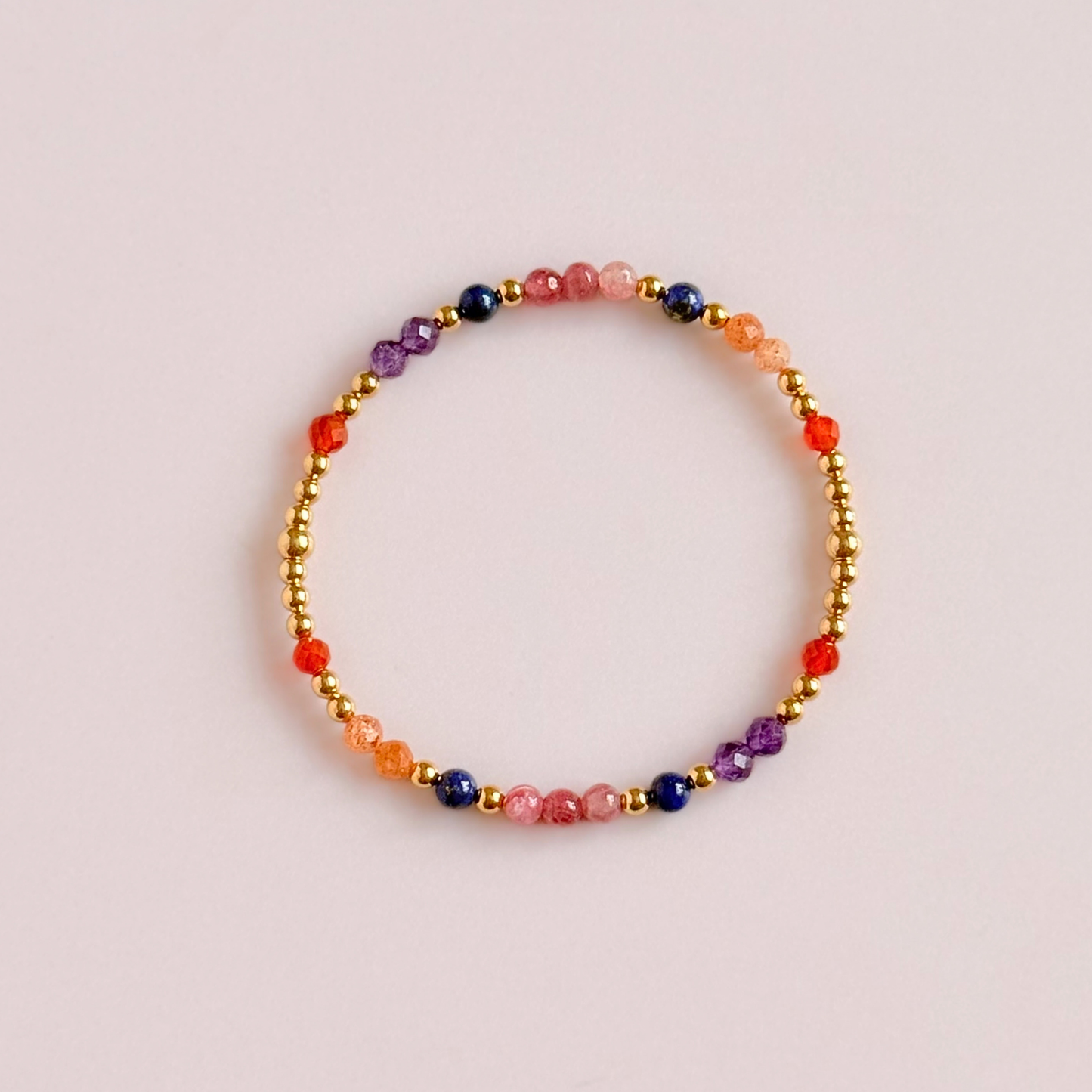 ‘Arabian Sunset' gold vermeil dainty beaded bracelet with pink tourmaline, sunstone, carnelian, lapis lazuli and amethyst. Made with round 3mm gold vermeil beads and 4mm smooth and faceted round crystal gemstone beads. Pictured from above, against a pink background