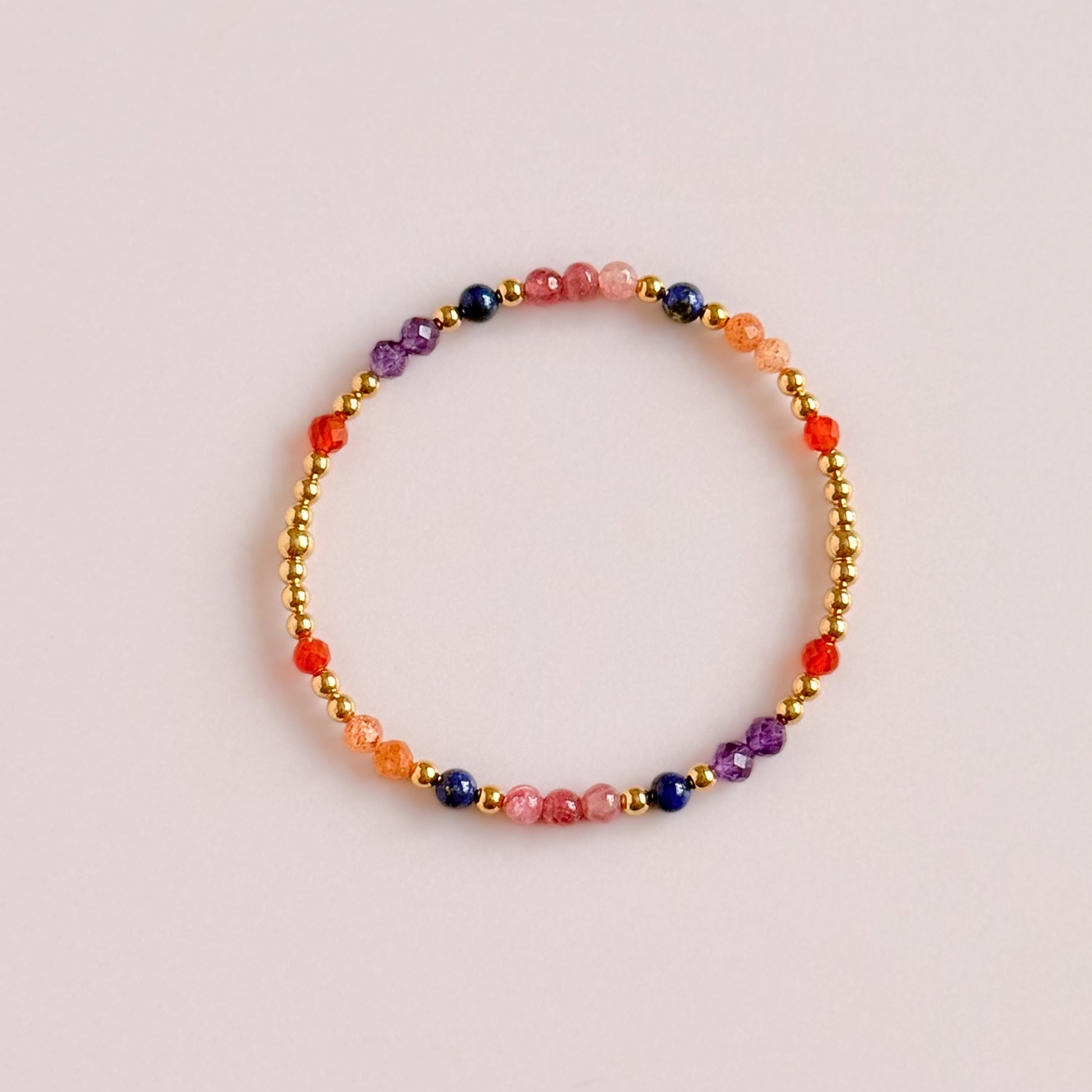 ‘Arabian Sunset' gold vermeil dainty beaded bracelet with pink tourmaline, sunstone, carnelian, lapis lazuli and amethyst. Made with round 3mm gold vermeil beads and 4mm smooth and faceted round crystal gemstone beads. Pictured from above, against a pink background