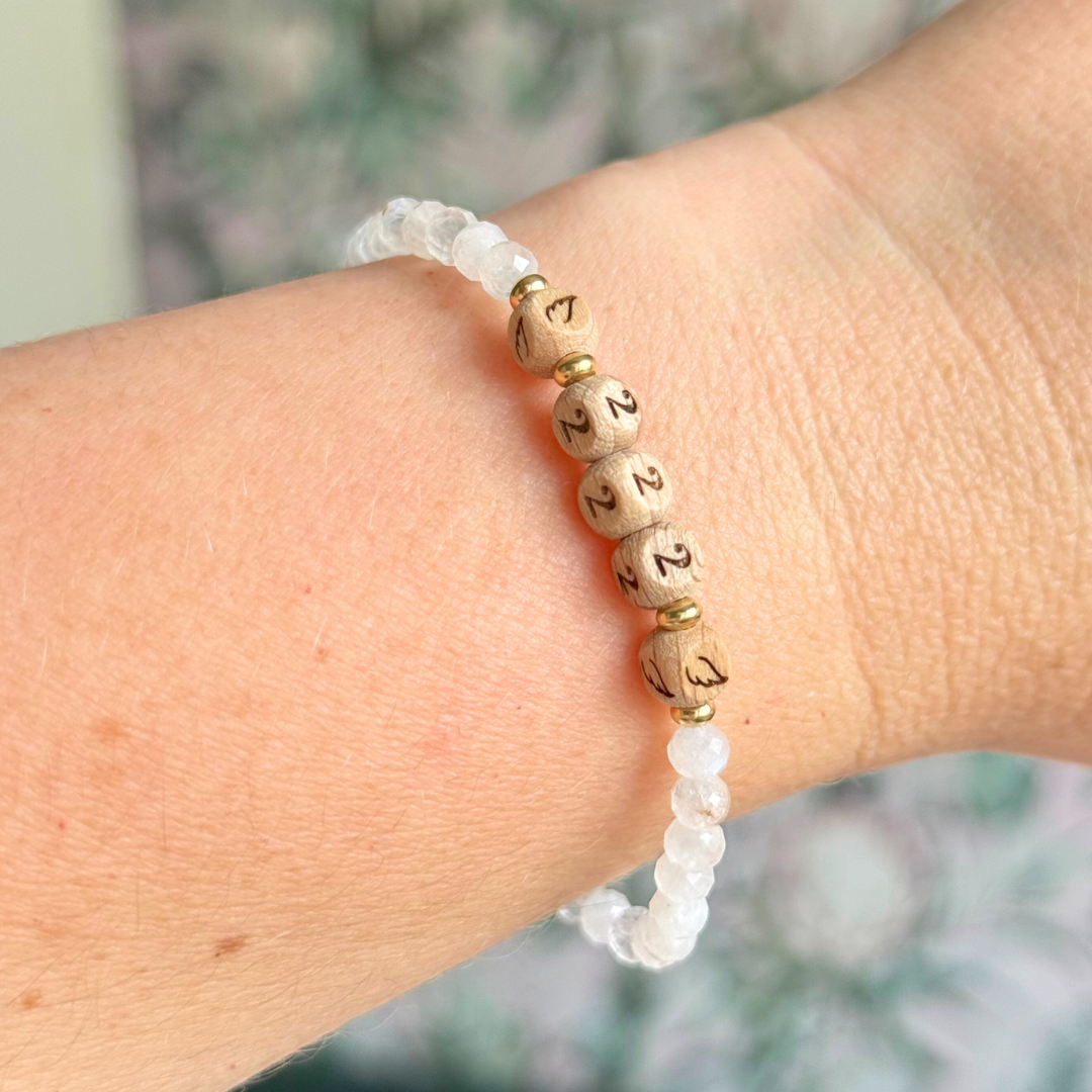 Bracelet featuring engraved wooden 222 angel number and wing beads, on the band of 4mm faceted moonstone round crystal gemstone beads. Finished with your choice of gold vermeil, sterling silver or rose gold vermeil accent beads.
