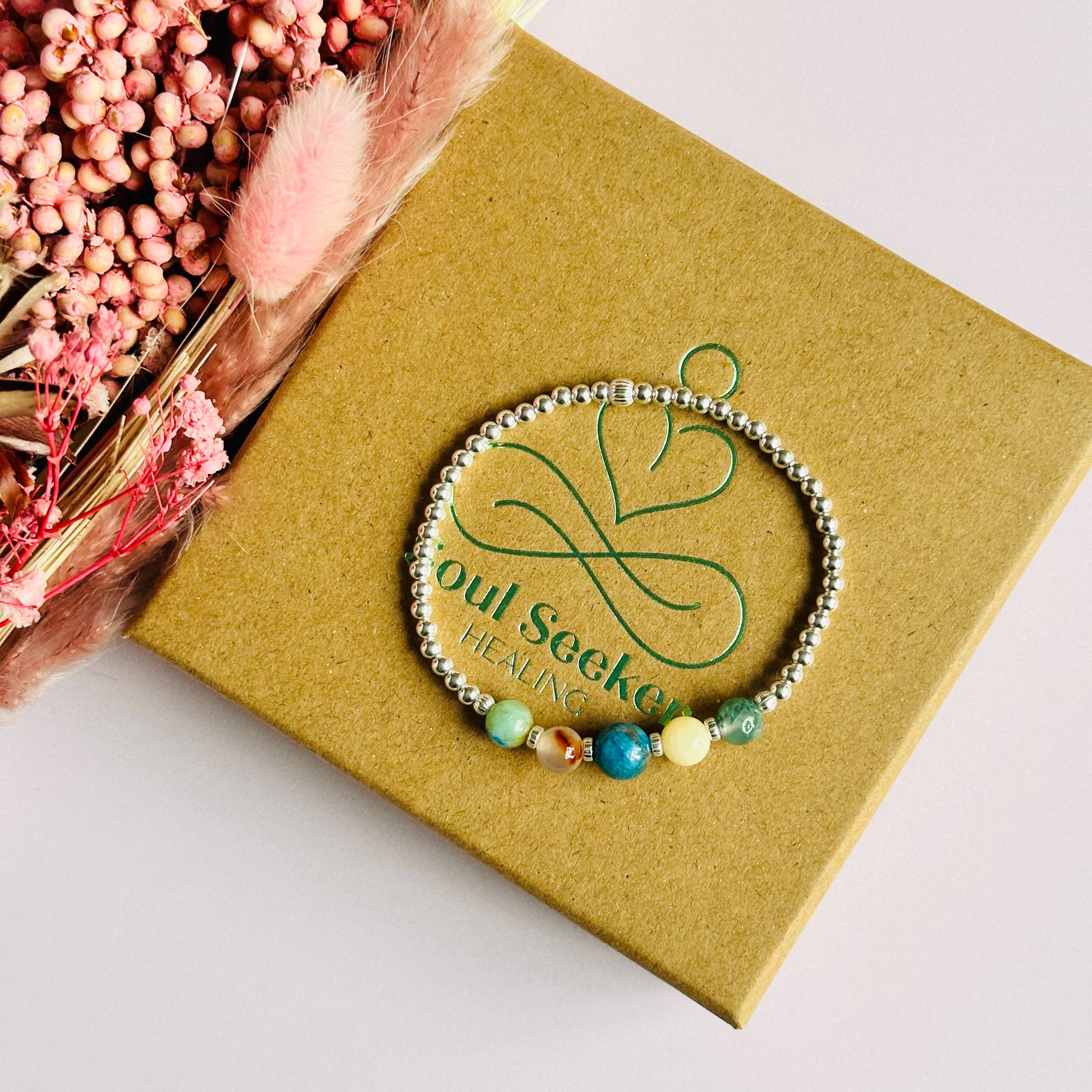 This sterling silver Gemini bracelet is made with a selection of five healing crystals all believed to resonate with the Gemini zodiac sign. The central bead is 8mm, the other four are 6mm. On an elasticated band of 3mm sterling silver beads with corrugated accent beads. Featuring chrysocolla, dendritic agate, apatite, yellow calcite and moss agate.