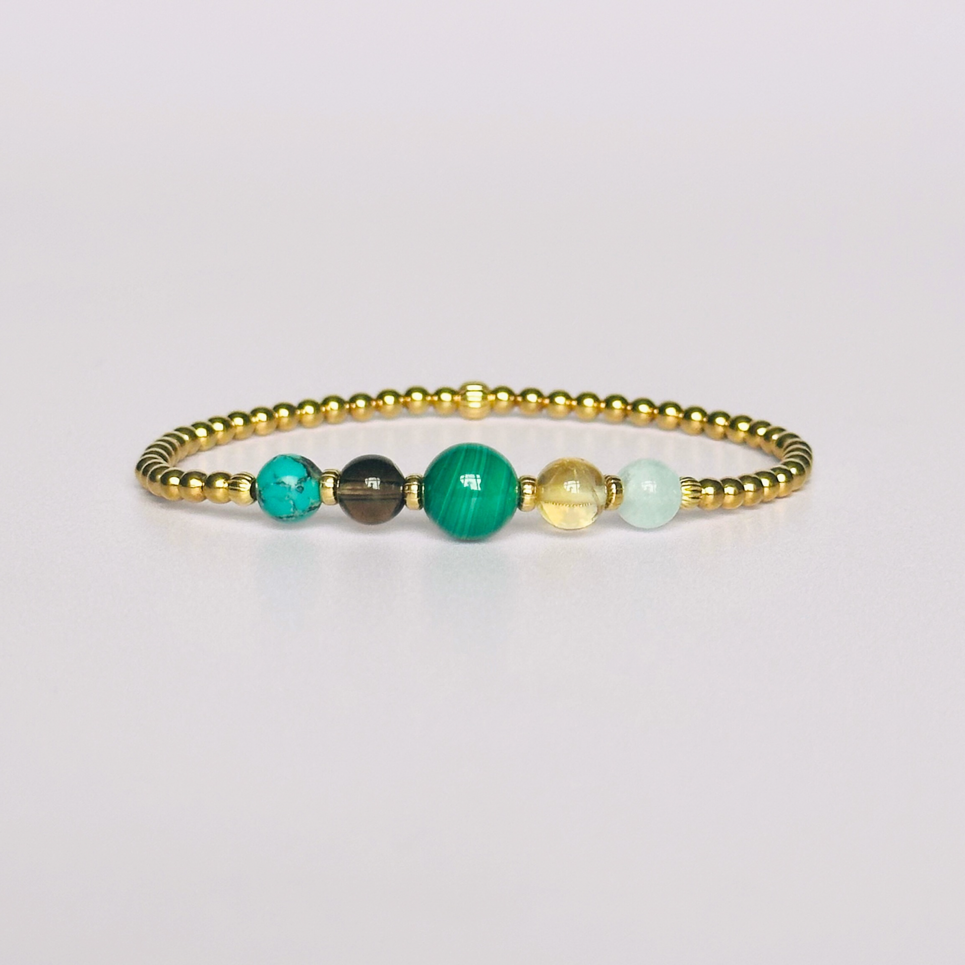 This gold vermeil Scorpio bracelet is made with a selection of five healing crystals all believed to resonate with the Scorpio zodiac sign. The central bead is 8mm, the other four are 6mm. On an elasticated band of 3mm gold vermeil beads with corrugated accent beads. Featuring aquamarine, citrine, malachite, smoky quartz and turquoise.