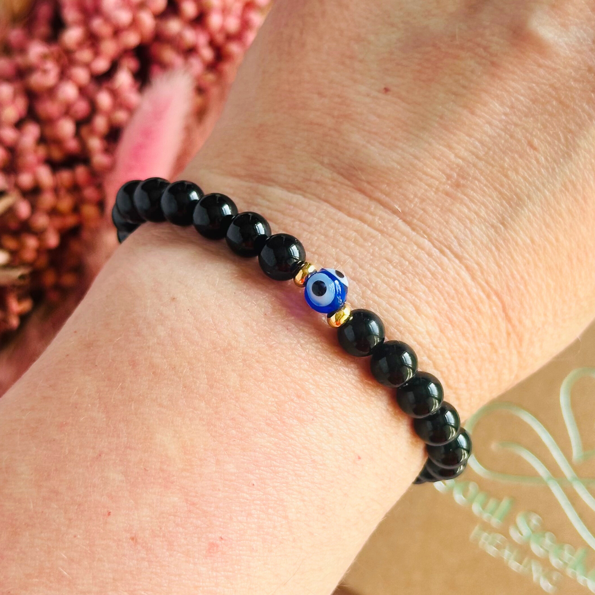 Natural black tourmaline bracelet featuring ethically mined smooth 6mm round beads with a beautiful blue Turkish evil eye glass bead as the focal point. Finished with gold vermeil or sterling silver accent beads.