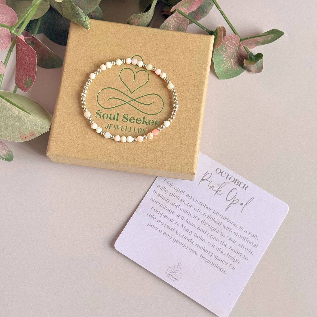 Dainty, minimalist sterling silver and pink opal October birthstone stacking bracelet. Made with 4mm faceted pink opal beads and 3mm sterling silver round beads. Elasticated for comfort. Pictured on top of the gift box, with the crystal information card.