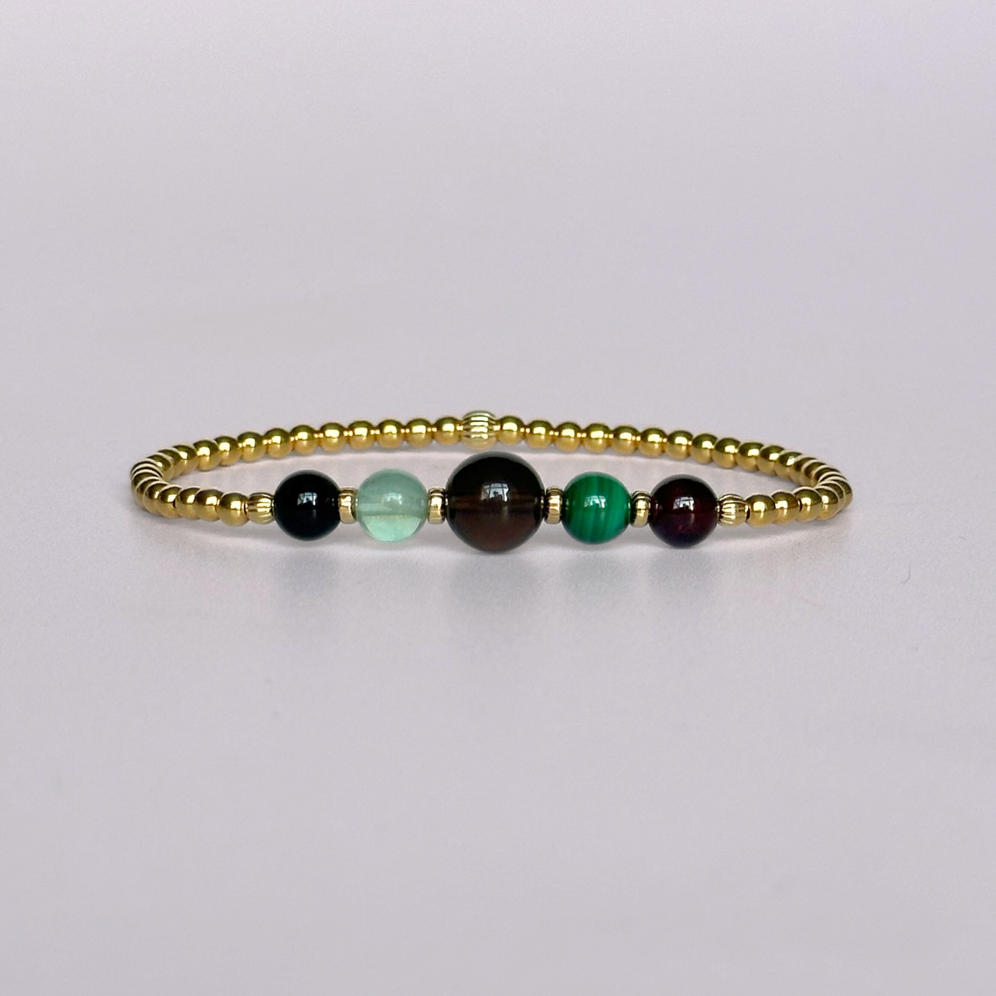 This gold vermeil Capricorn bracelet is made with a selection of five healing crystals all believed to resonate with the Capricorn zodiac sign. The central bead is 8mm, the other four are 6mm. On an elasticated band of 3mm gold vermeil beads with corrugated accent beads. Featuring garnet, malachite, fluorite, smoky quartz and black tourmaline.