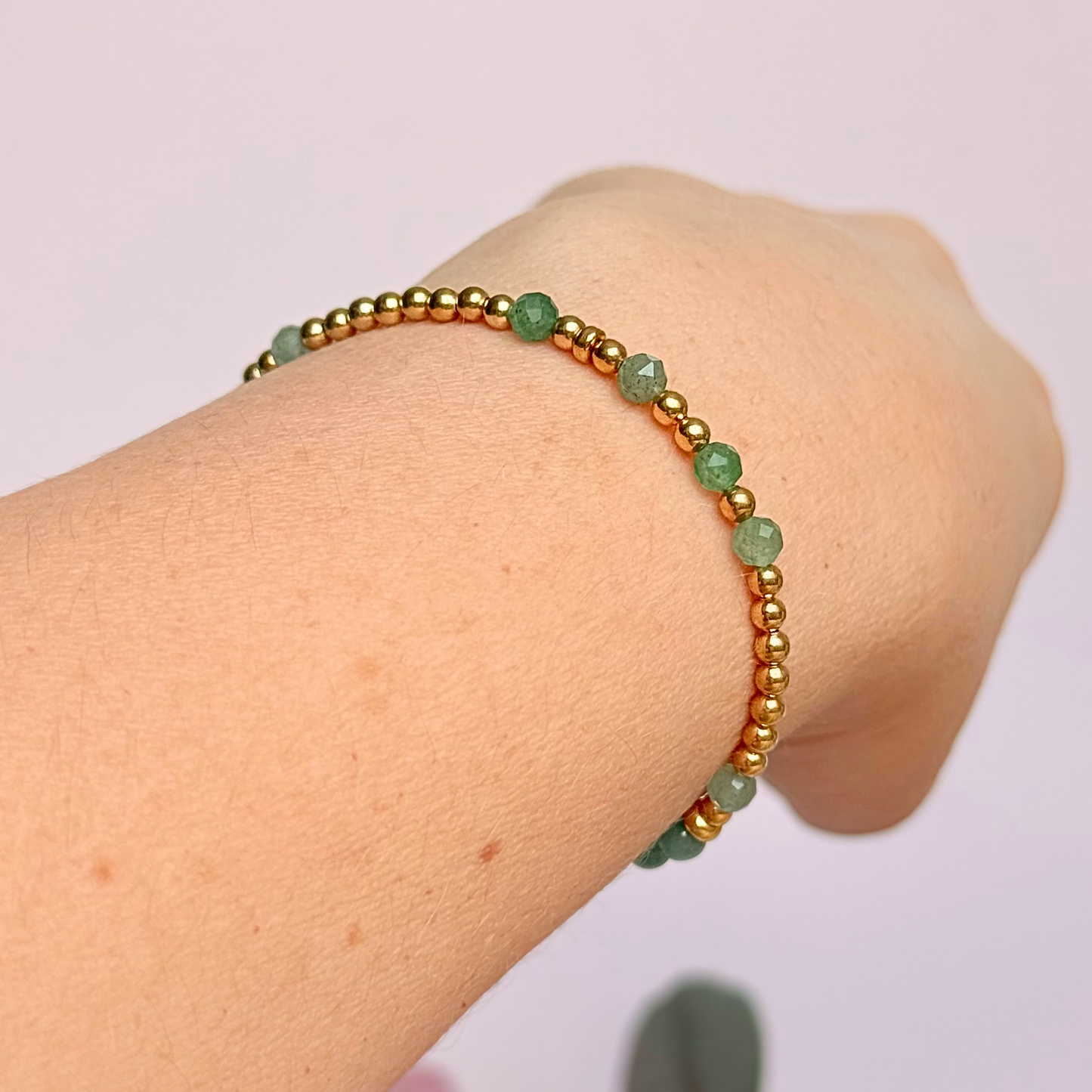 Green aventurine morse code bracelet that spells out the words ‘Ask, believe, receive’ in a combination of 4mm round smooth and faceted crystal beads with your choice of sterling silver or gold vermeil accent beads. Pictured in gold, being worn at an angle