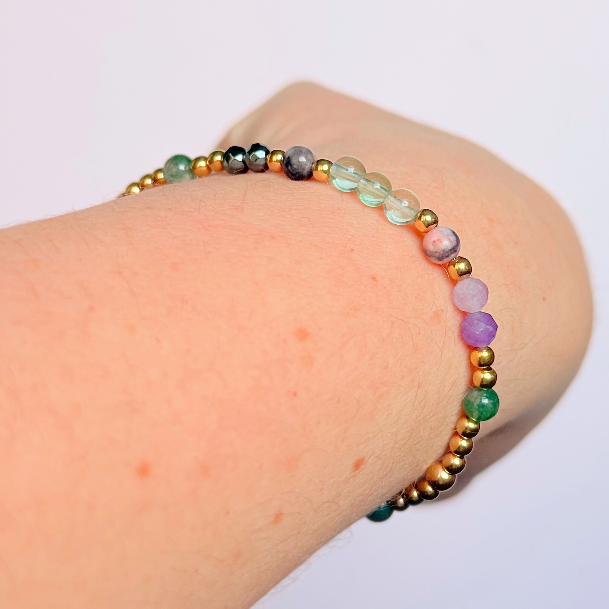 Dainty crystal bracelet featuring five crystals all believed to help with focus, clarity and overwhelm. Featuring fluorite, hematite, lepidolite, moss agate and pink zebra jasper. Featuring 3mm gold vermeil round beads and 4mm faceted round and smooth round crystal beads. Pictured being worn, on an angle.￼