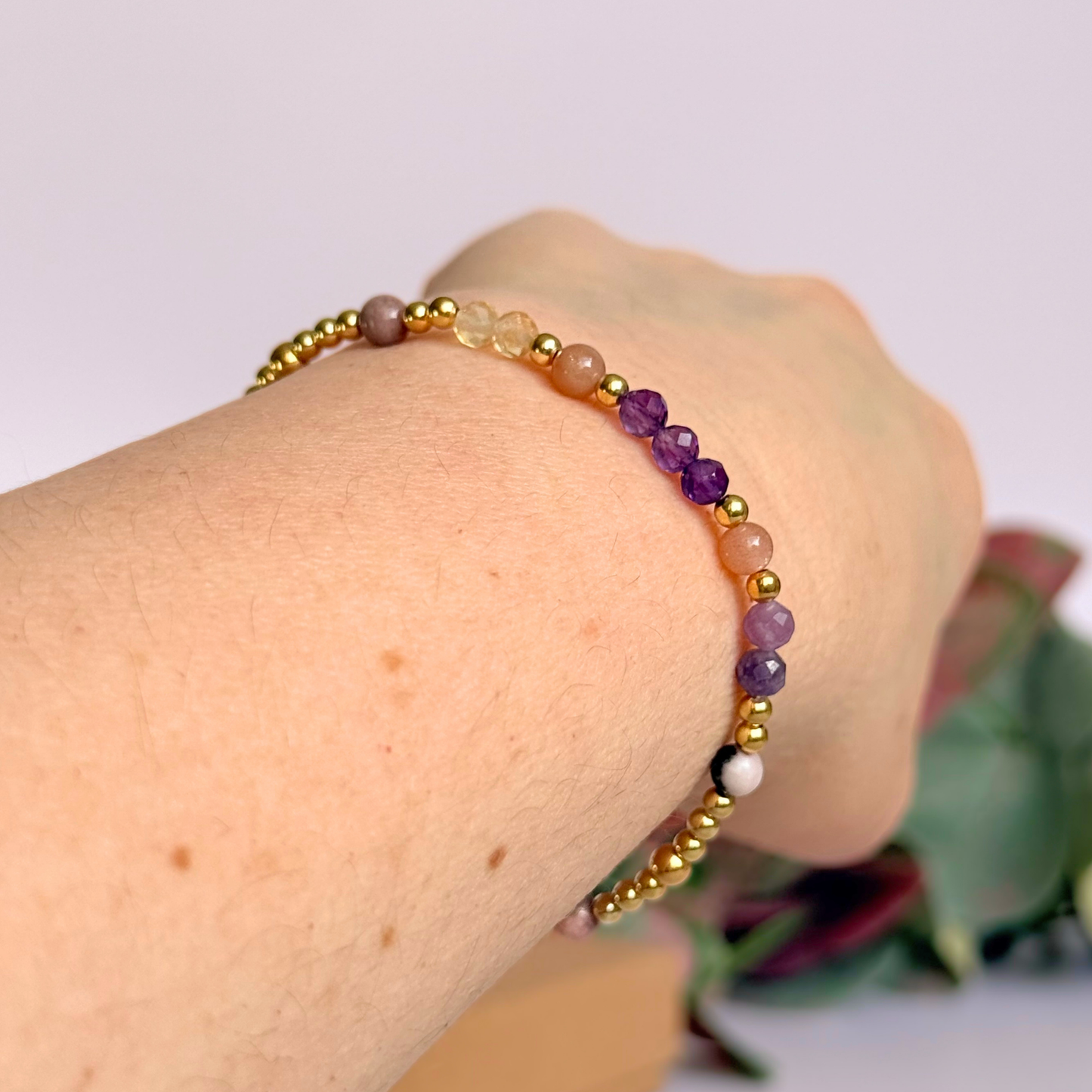 Dainty gold vermeil crystal bracelet featuring five crystals, in 4mm faceted and smooth round style, each believed to help with menopause symptoms. Featuring amethyst, citrine, lepidolite, peach moonstone and pink zebra jasper. Pictured being worn, on an angle.