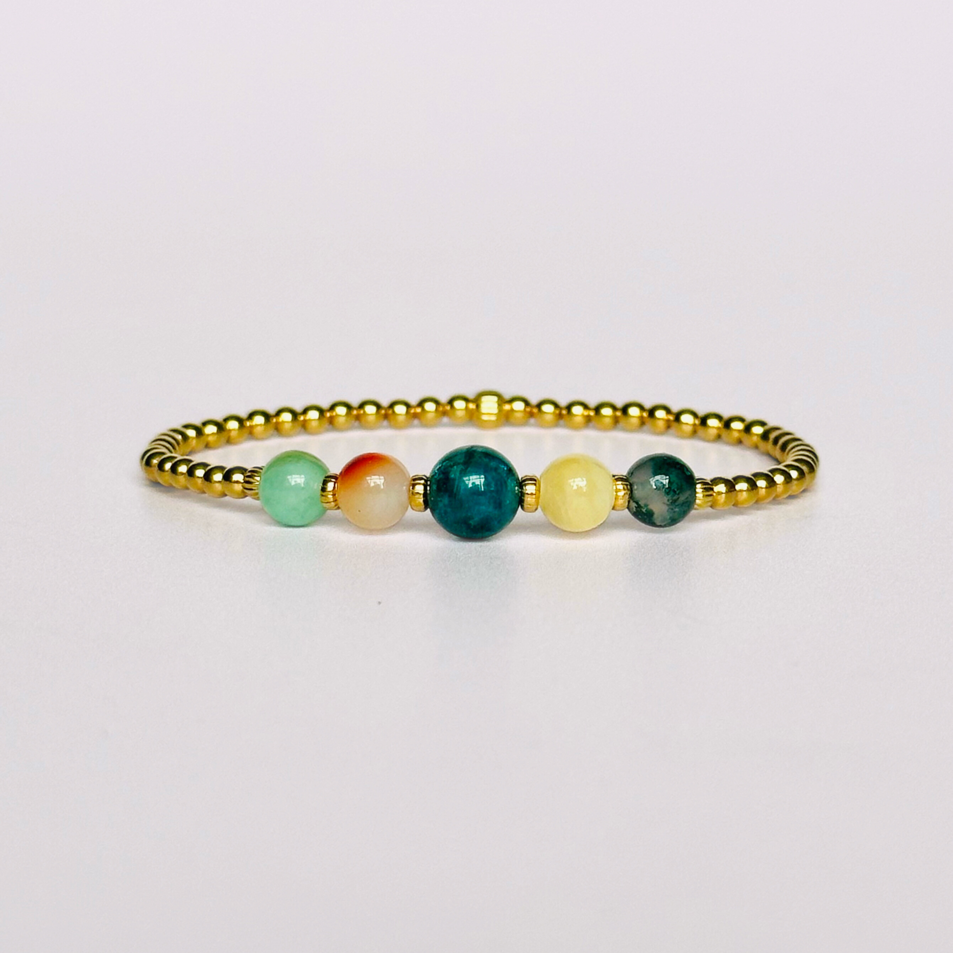 This gold vermeil Gemini bracelet is made with a selection of five healing crystals all believed to resonate with the Gemini zodiac sign. The central bead is 8mm, the other four are 6mm. On an elasticated band of 3mm gold vermeil beads with corrugated accent beads. Featuring chrysocolla, dendritic agate, apatite, yellow calcite and moss agate.
