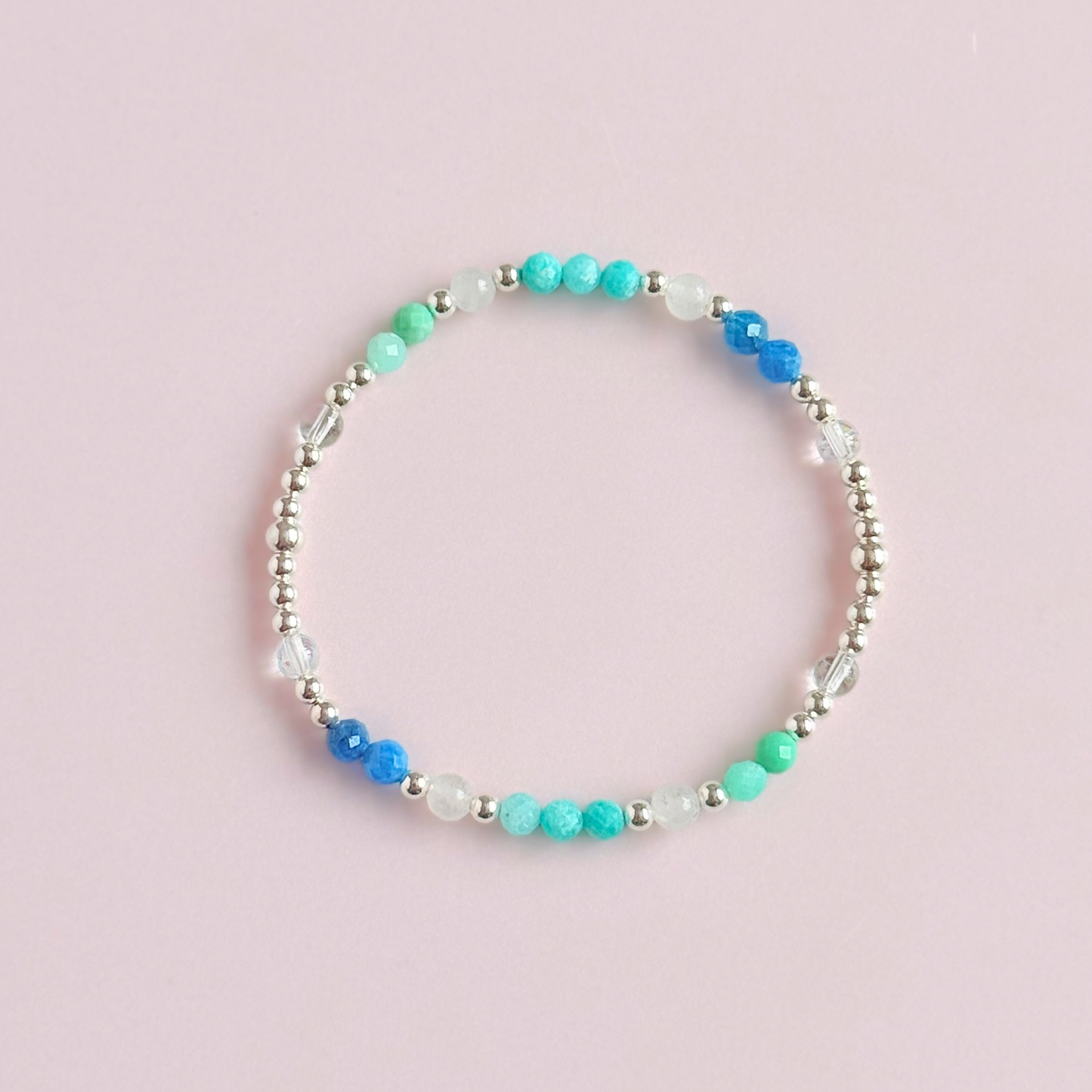 ‘Caribbean Dream' sterling silver dainty beaded bracelet with white jade, chrysoprase, amazonite, apatite and clear quartz. Made with round 3mm sterling silver beads and 4mm smooth and faceted round crystal gemstone beads. Pictured from above, on a pink background