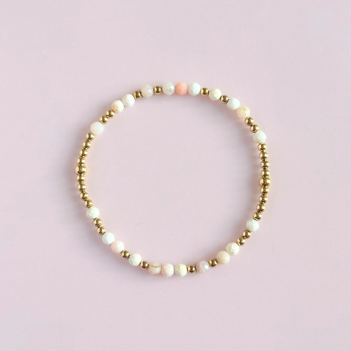 Dainty, minimalist gold vermeil and pink opal October birthstone stacking bracelet. Made with 4mm faceted pink opal beads and 3mm gold vermeil round beads. Elasticated for comfort. Pictured from above