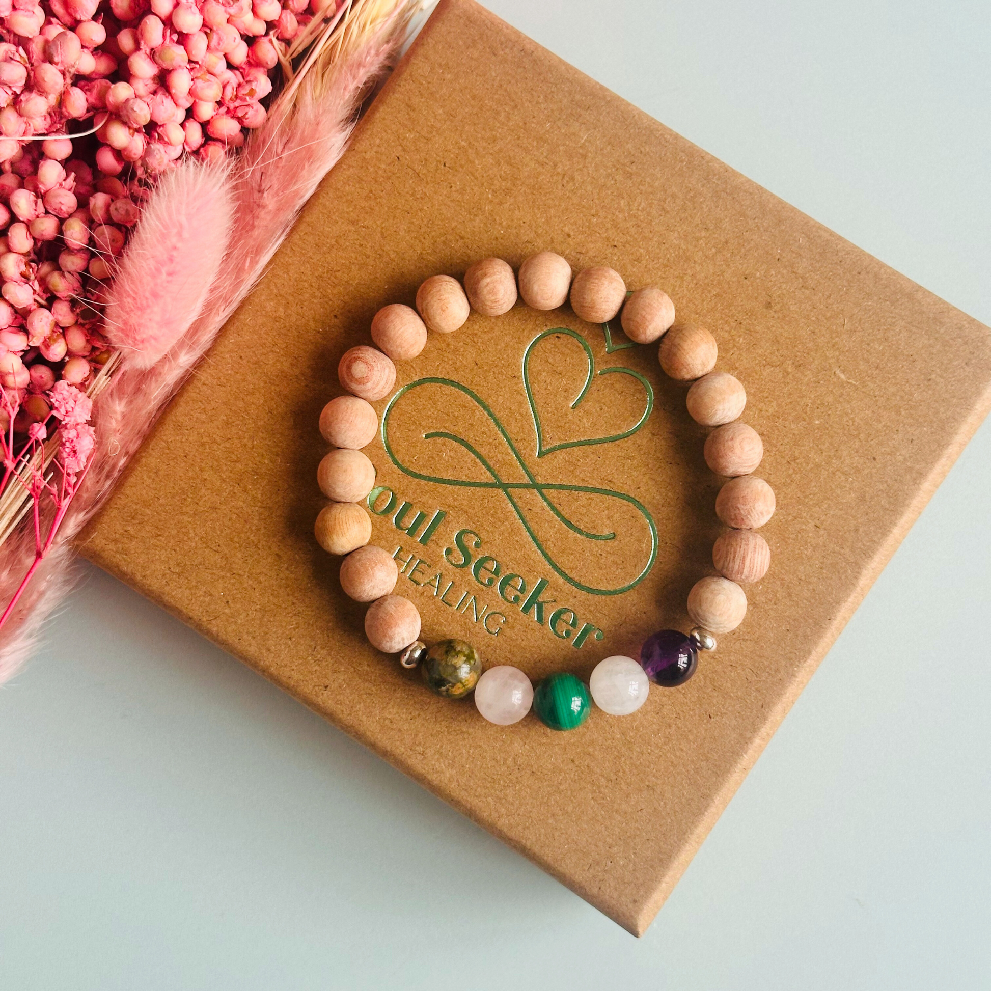 Essential oil diffuser bracelet featuring five crystal beads, all thought to aid in having a healthy pregnancy. Featuring unakite, rose quartz, amethyst, malachite and moonstne with raw rosewood beads that can act as a diffuser for essential oils.
