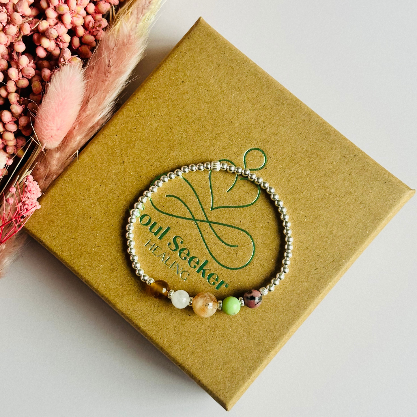 This sterling silver Cancer bracelet is made with a selection of five healing crystals all believed to resonate with the Cancer zodiac sign. The central bead is 8mm, the other four are 6mm. On an elasticated band of 3mm sterling silver beads with corrugated accent beads. Featuring chrysoprase, rhodonite, sunstone, carnelian and moonstone.