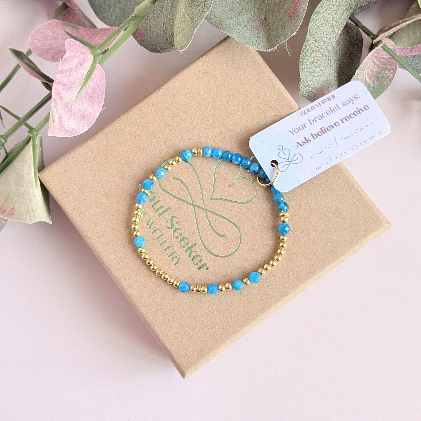 Apatite morse code bracelet that spells out the words ‘Ask, believe, receive’ in a combination of 4mm round smooth and faceted crystal beads with your choice of sterling silver or gold vermeil accent beads. Pictured in gold, on top of gift box