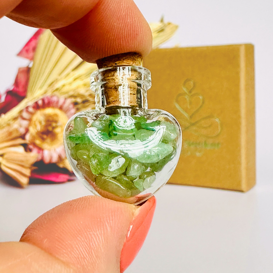 A pretty heart shaped mini glass bottle filled with powerful, ethically mined green aventurine crystal chips, known for their properties regarding good luck, abundance and success. Presented on a card with the words ‘may good luck be your constant companion.’ This bottle measures approximately 28mm x 23mm, including cork when it is pushed in.