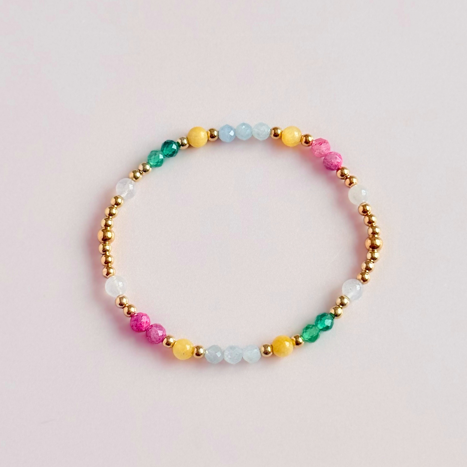 'Amalfi Coast' gold vermeil dainty beaded bracelet with green agate, yellow calcite, pink tourmaline, aquamarine and moonstone. Made with round 3mm gold vermeil beads and 4mm smooth and faceted round crystal gemstone beads. Pictured from above, on a pink background