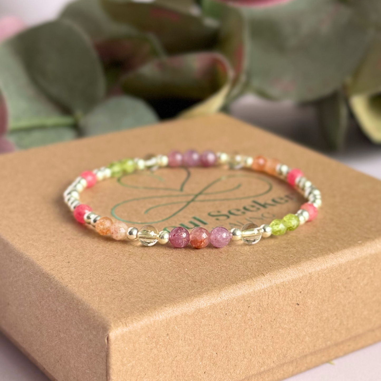 Dainty crystal bracelet featuring a carefully curated selection of genuine crystal beads inspired by wildflowers and free-spirited growth. Featuring 4mm smooth and faceted round gemstone beads with 3mm round accent beads in either sterling silver or gold vermeil. With peridot, sunstone, rhodochrosite, citrine and lepidolite. Pictured in silver, on top of the gift box.