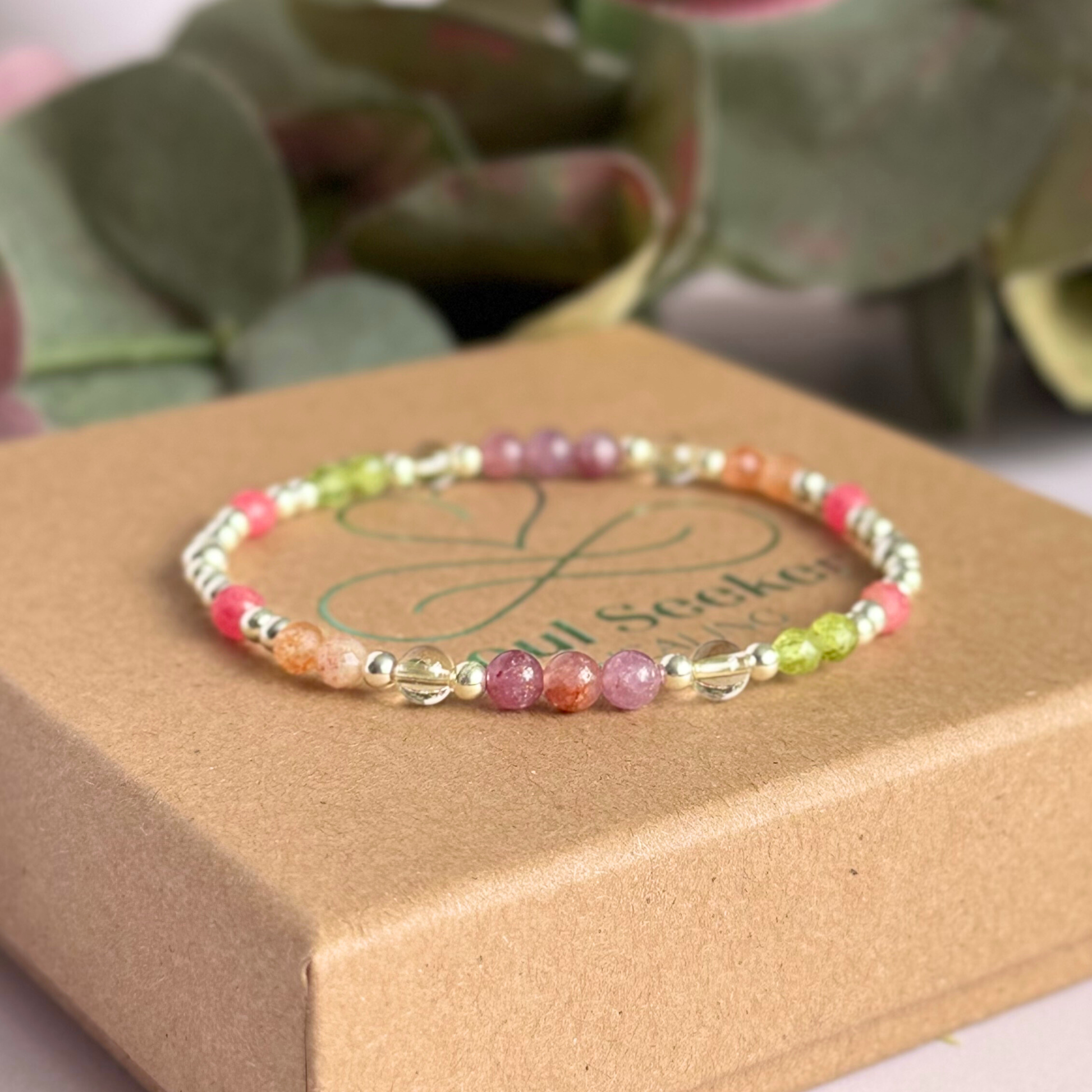 Dainty crystal bracelet featuring a carefully curated selection of genuine crystal beads inspired by wildflowers and free-spirited growth. Featuring 4mm smooth and faceted round gemstone beads with 3mm round accent beads in either sterling silver or gold vermeil. With peridot, sunstone, rhodochrosite, citrine and lepidolite. Pictured in silver, on top of the gift box.