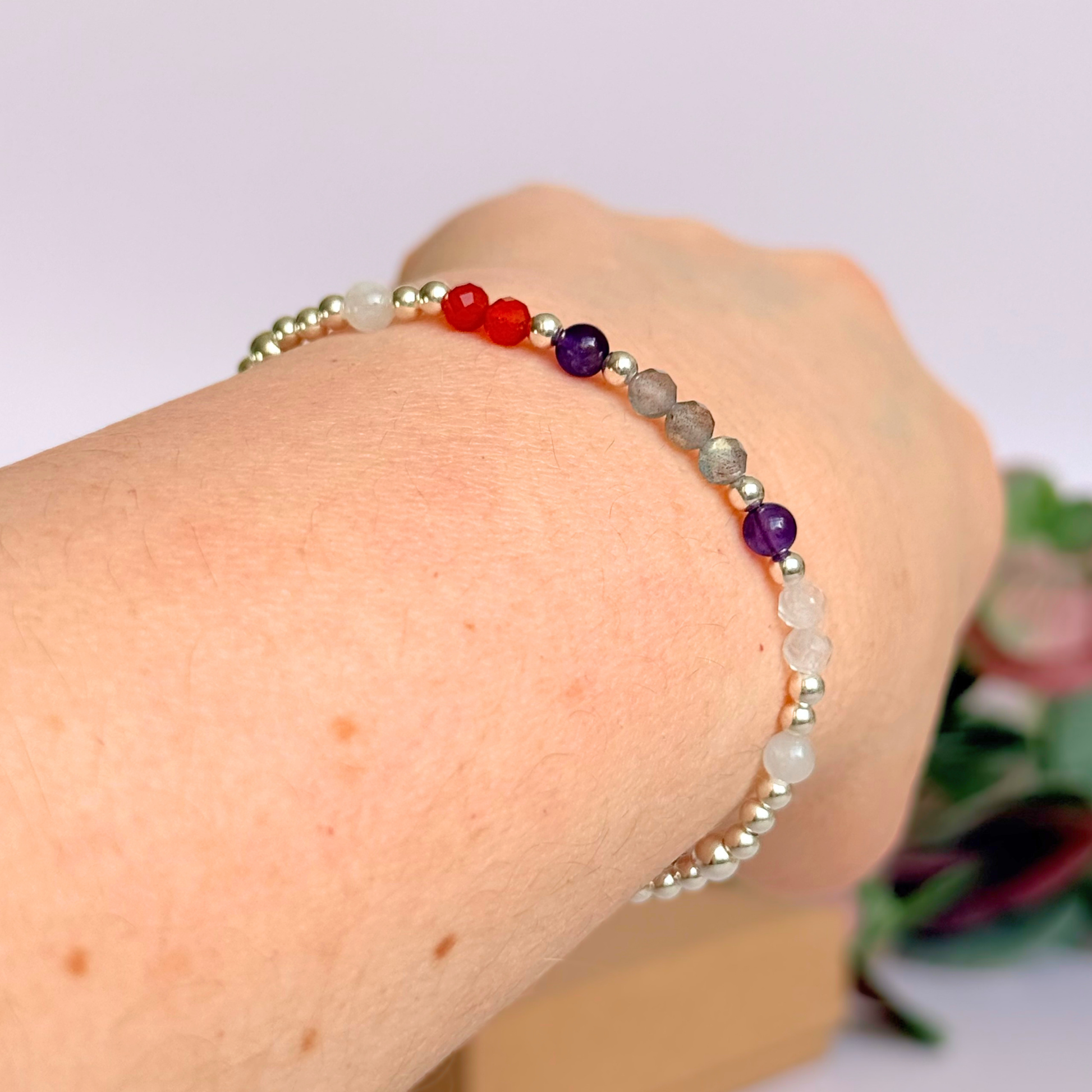 Dainty sterling silver crystal bracelet featuring five crystals, in 4mm faceted and smooth round style, each believed to help with hormonal balance. Featuring amethyst, moonstone, carnelian, labradorite and rose quartz. Pictured being worn, shown on an angle.