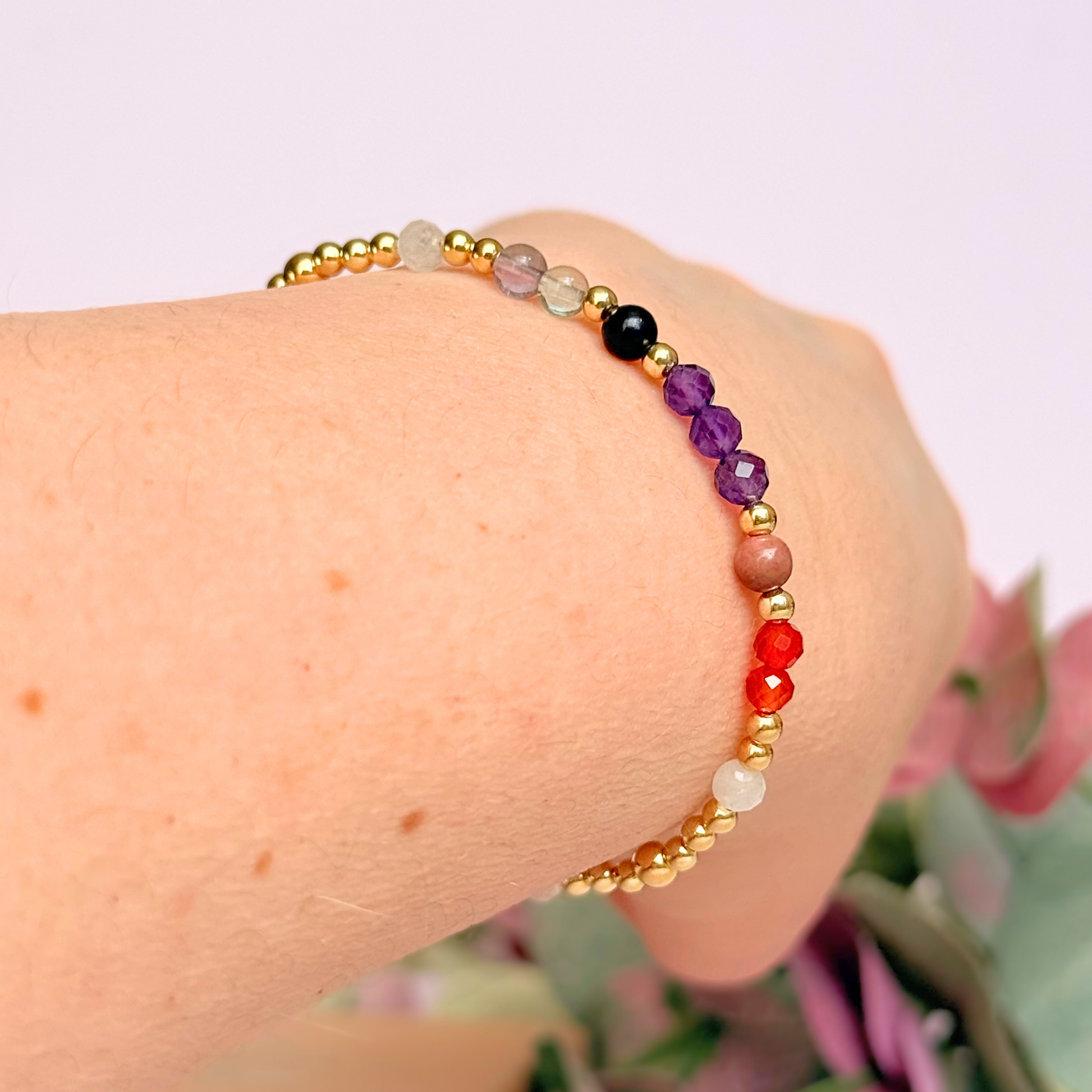 Dainty gold vermeil crystal bracelet featuring five crystals, in 4mm faceted and smooth round style, each believed to help with perimenopause symptoms. Featuring amethyst, rhodonite, fluorite, moonstone and carnelian. Pictured being worn, on an angle.