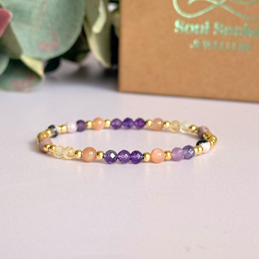 Dainty gold vermeil crystal bracelet featuring five crystals, in 4mm faceted and smooth round style, each believed to help with menopause symptoms. Featuring amethyst, citrine, lepidolite, peach moonstone and pink zebra jasper. Pictured in front of the gift box.