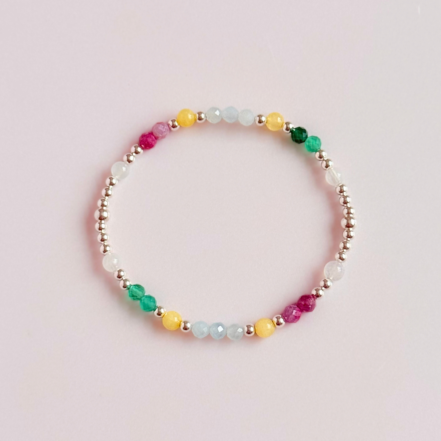 'Amalfi Coast' sterling silver dainty beaded bracelet with green agate, yellow calcite, pink tourmaline, aquamarine and moonstone. Made with round 3mm sterling silver beads and 4mm smooth and faceted round crystal gemstone beads. Pictured from above, against a pink background