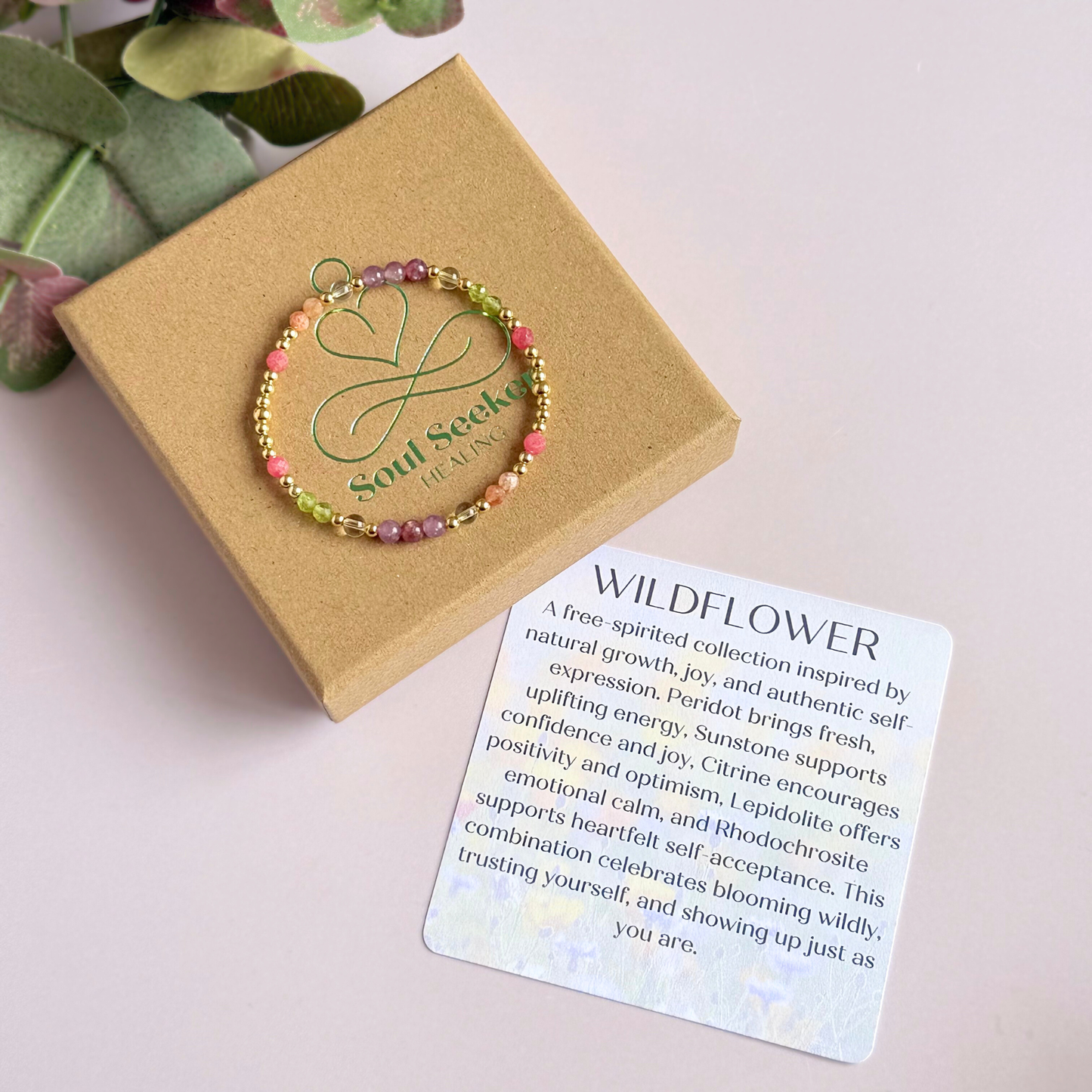 Dainty crystal bracelet featuring a carefully curated selection of genuine crystal beads inspired by wildflowers and free-spirited growth. Featuring 4mm smooth and faceted round gemstone beads with 3mm round accent beads in either sterling silver or gold vermeil. With peridot, sunstone, rhodochrosite, citrine and lepidolite. Picture features the bracelet in gold on top of the gift box with the crystal information card.