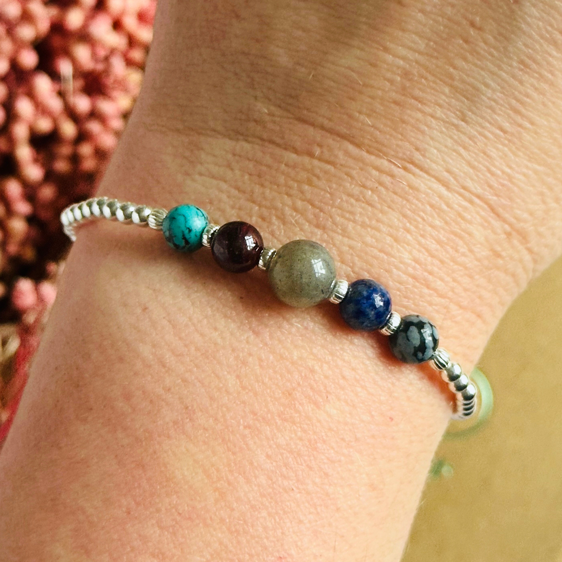 This sterling silver Sagittarius bracelet is made with a selection of five healing crystals all believed to resonate with the Sagittarius zodiac sign. The central bead is 8mm, the other four are 6mm. On an elasticated band of 3mm sterling silver beads with corrugated accent beads. Featuring garnet, labradorite, lapis lazuli, snowflake obsidian and turquoise.