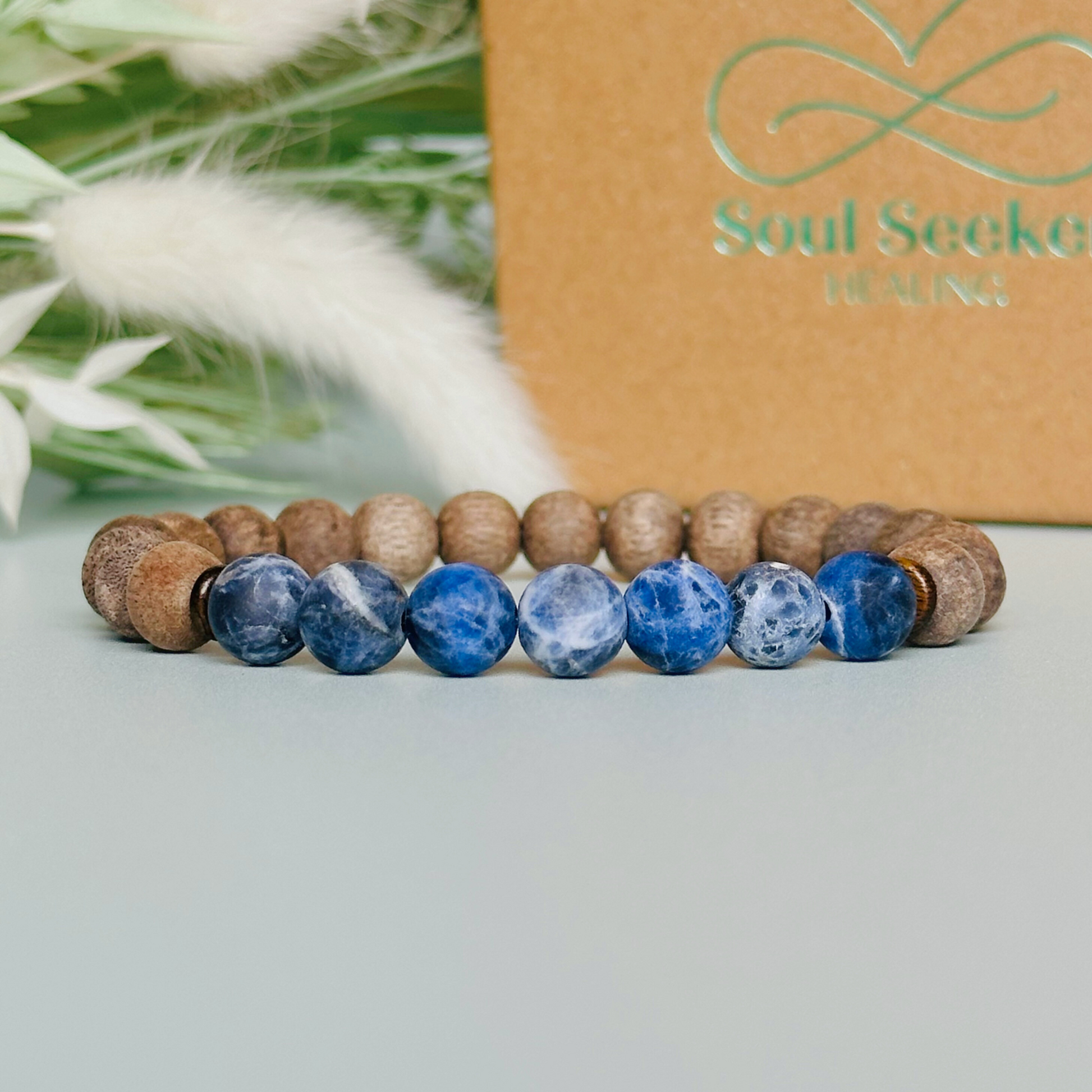 Mens crystal healing bracelet featuring 8mm frosted sodalite beads, grey wood beads and sandalwood spacer beads.