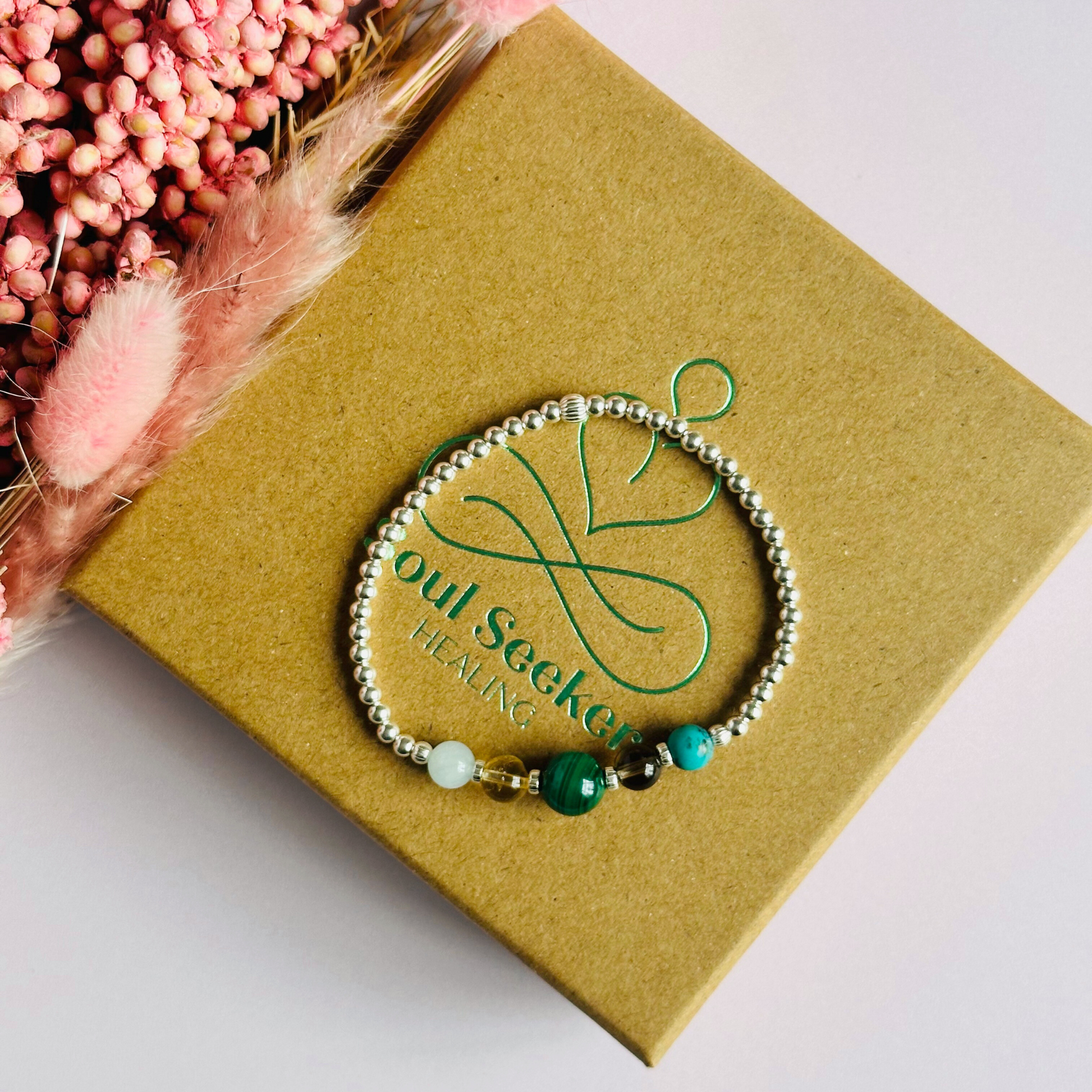 This sterling silver Scorpio bracelet is made with a selection of five healing crystals all believed to resonate with the Scorpio zodiac sign. The central bead is 8mm, the other four are 6mm. On an elasticated band of 3mm sterling silver beads with corrugated accent beads. Featuring aquamarine, citrine, malachite, smoky quartz and turquoise.
